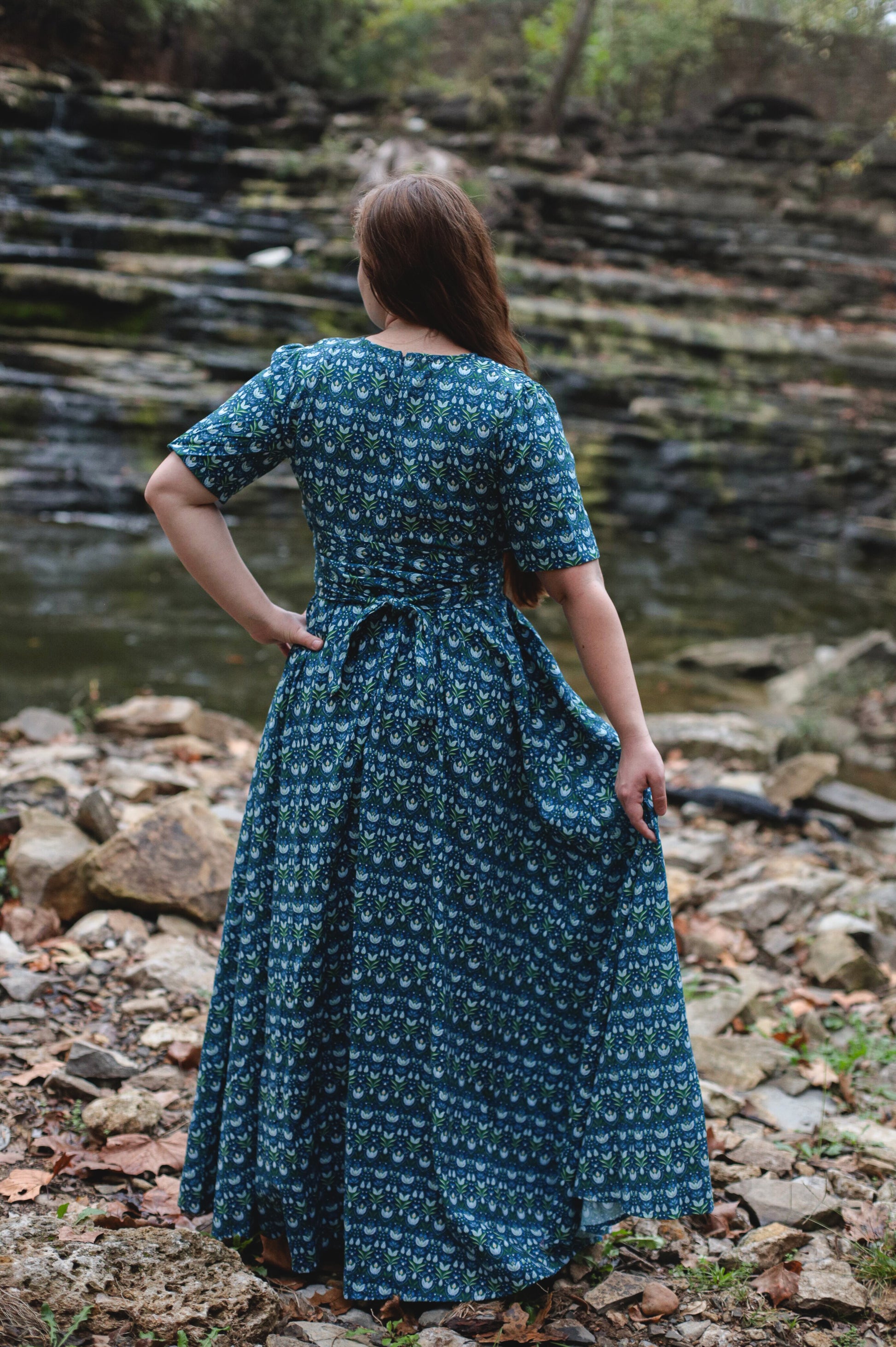 Woman in modest nursing dress by stream