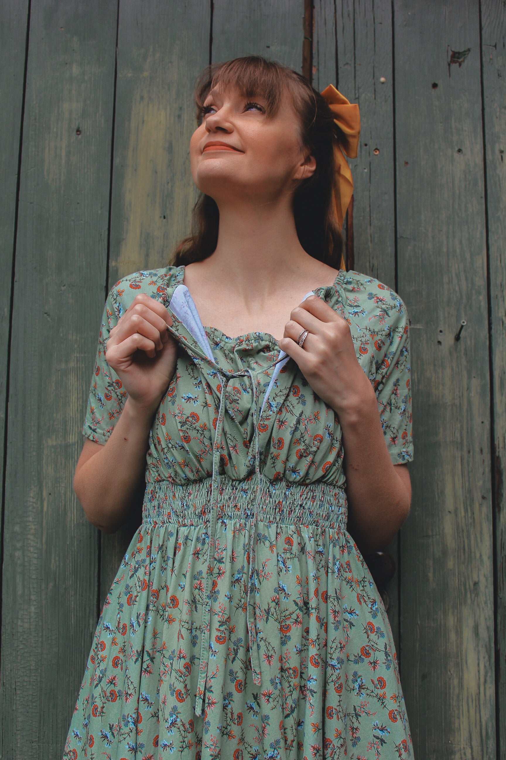 Woman in modest nursing floral dress by wall