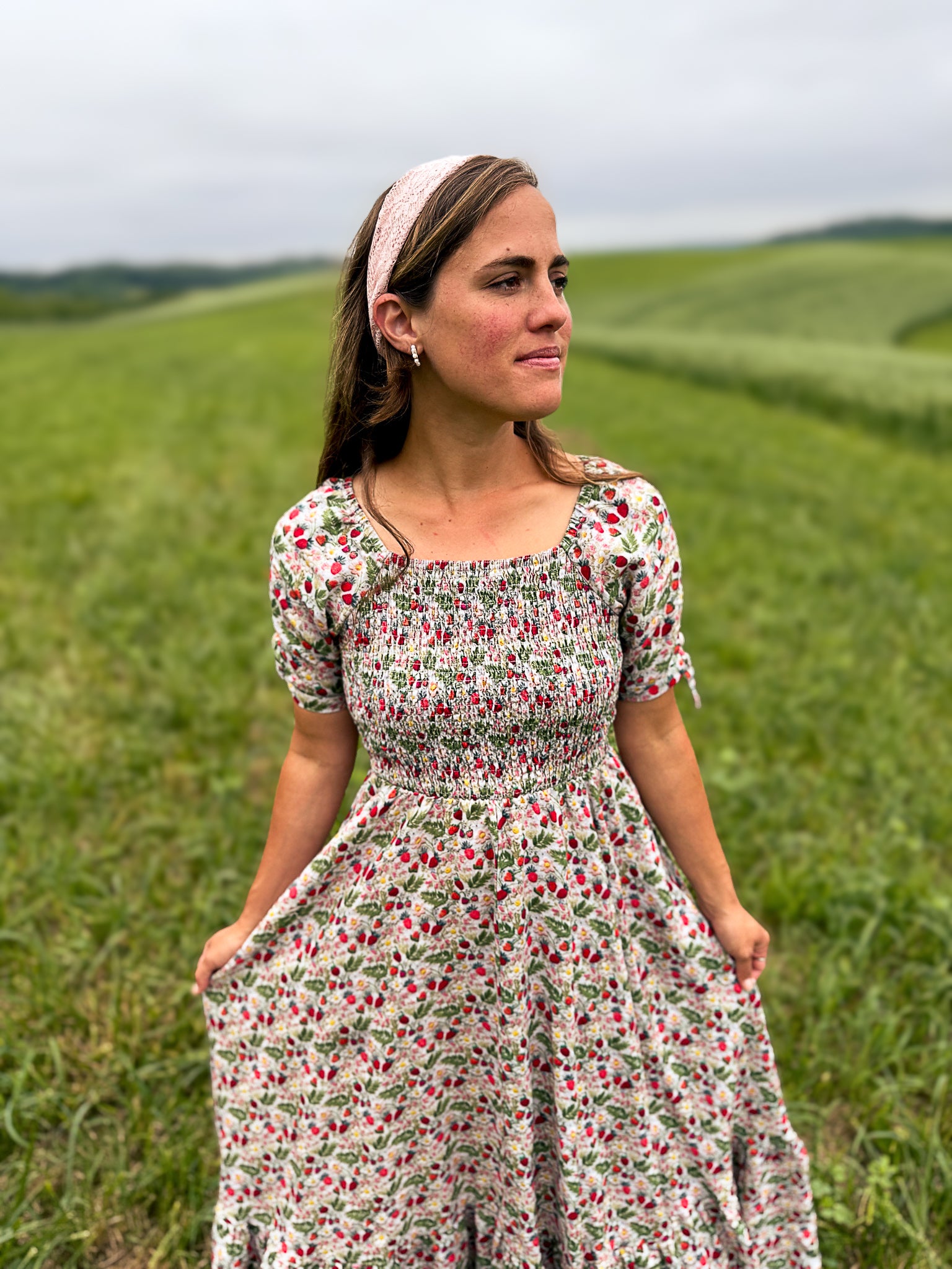 Woman in a floral modest nursing dress standing in a green field