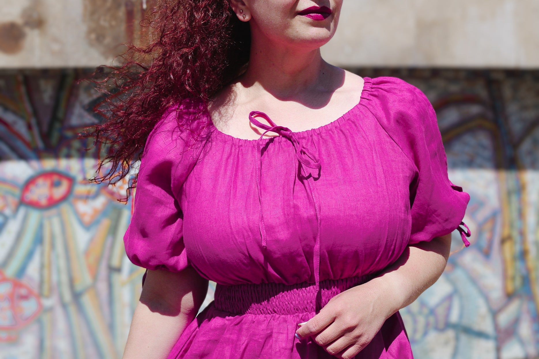 Woman wearing a pink modest nursing dress with a colorful mural in the background