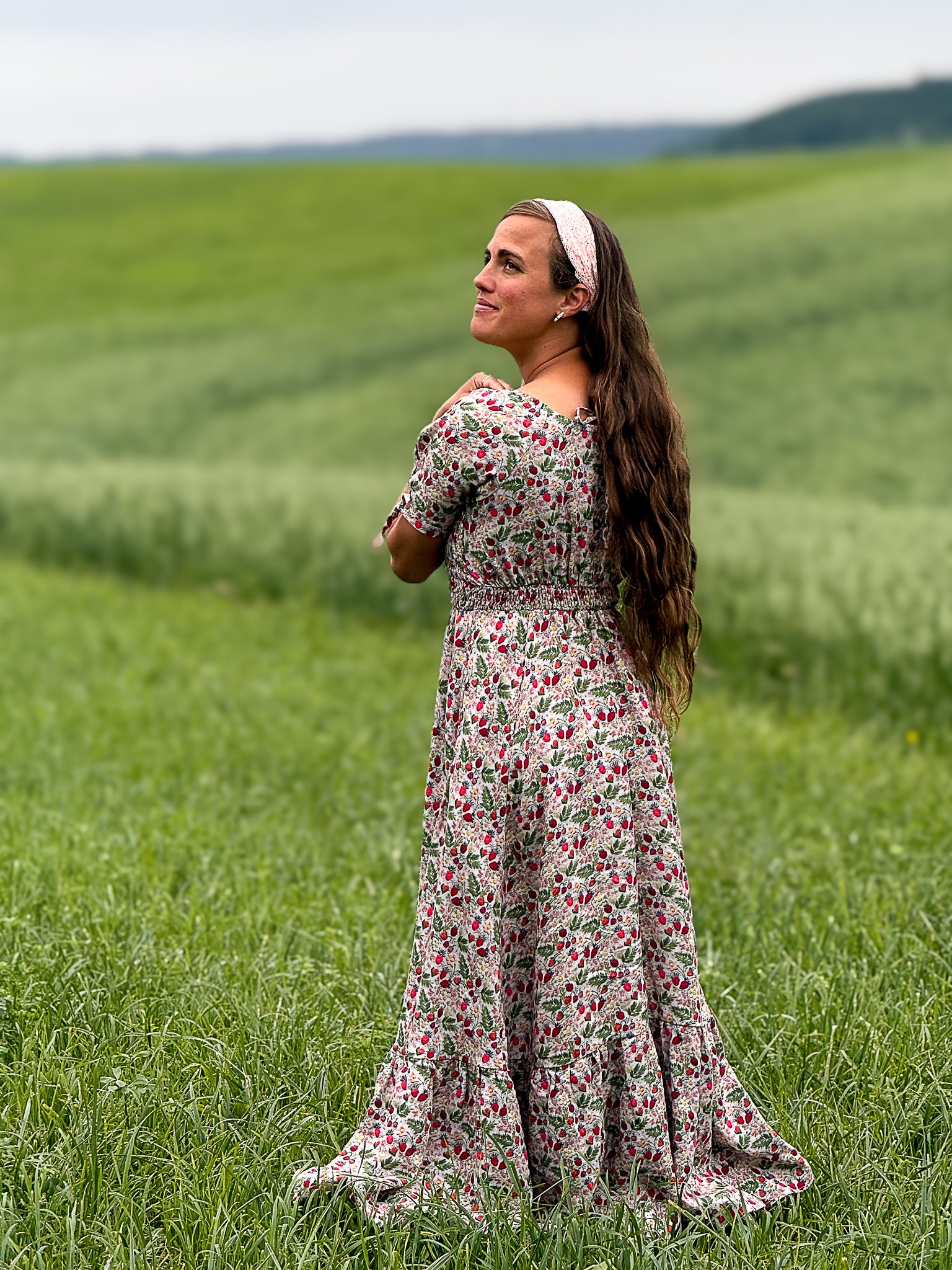 Woman in a floral modest nursing dress standing in a green field