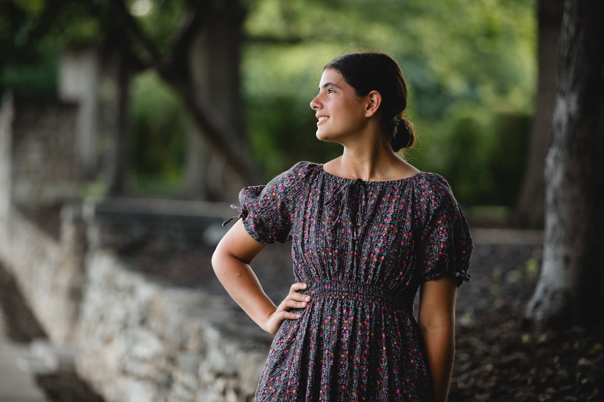 Woman in a floral modest nursing dress standing outdoors with trees in the background