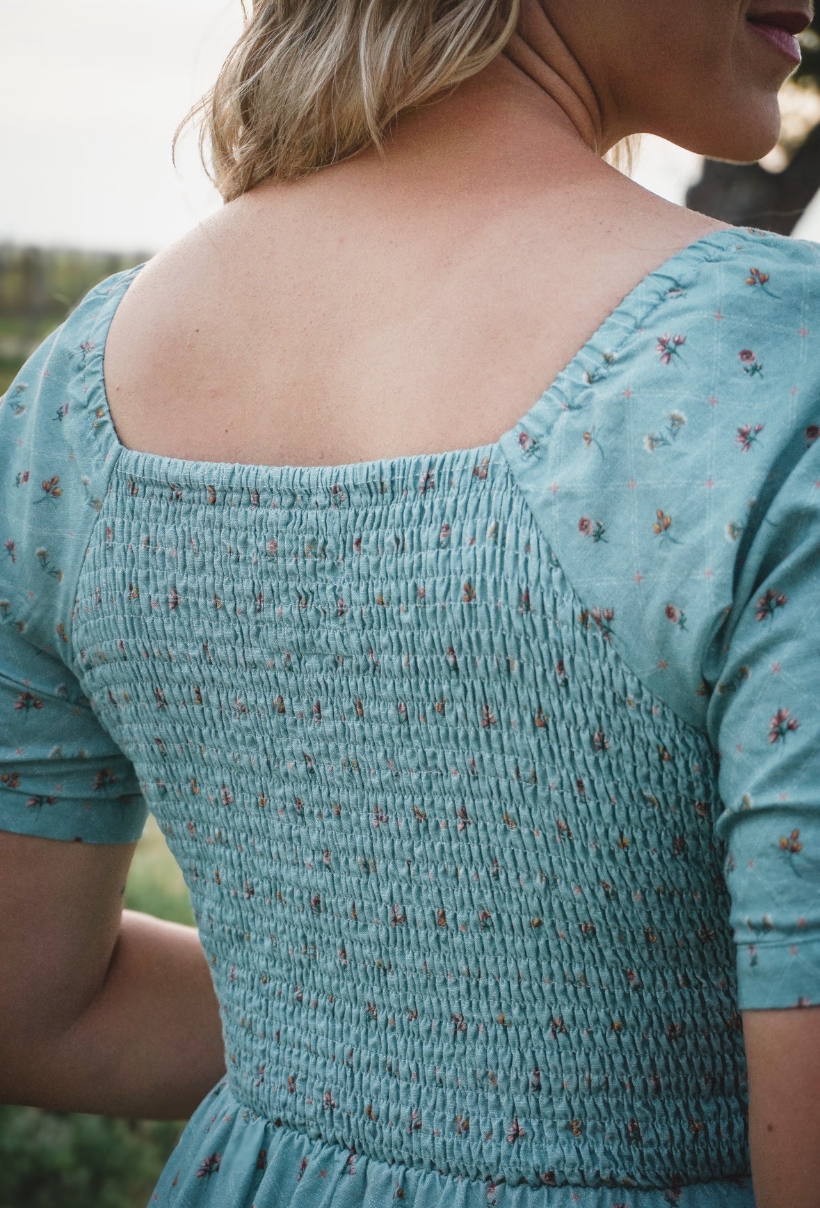 Close-up of a person wearing a blue modest nursing dress with floral patterns.