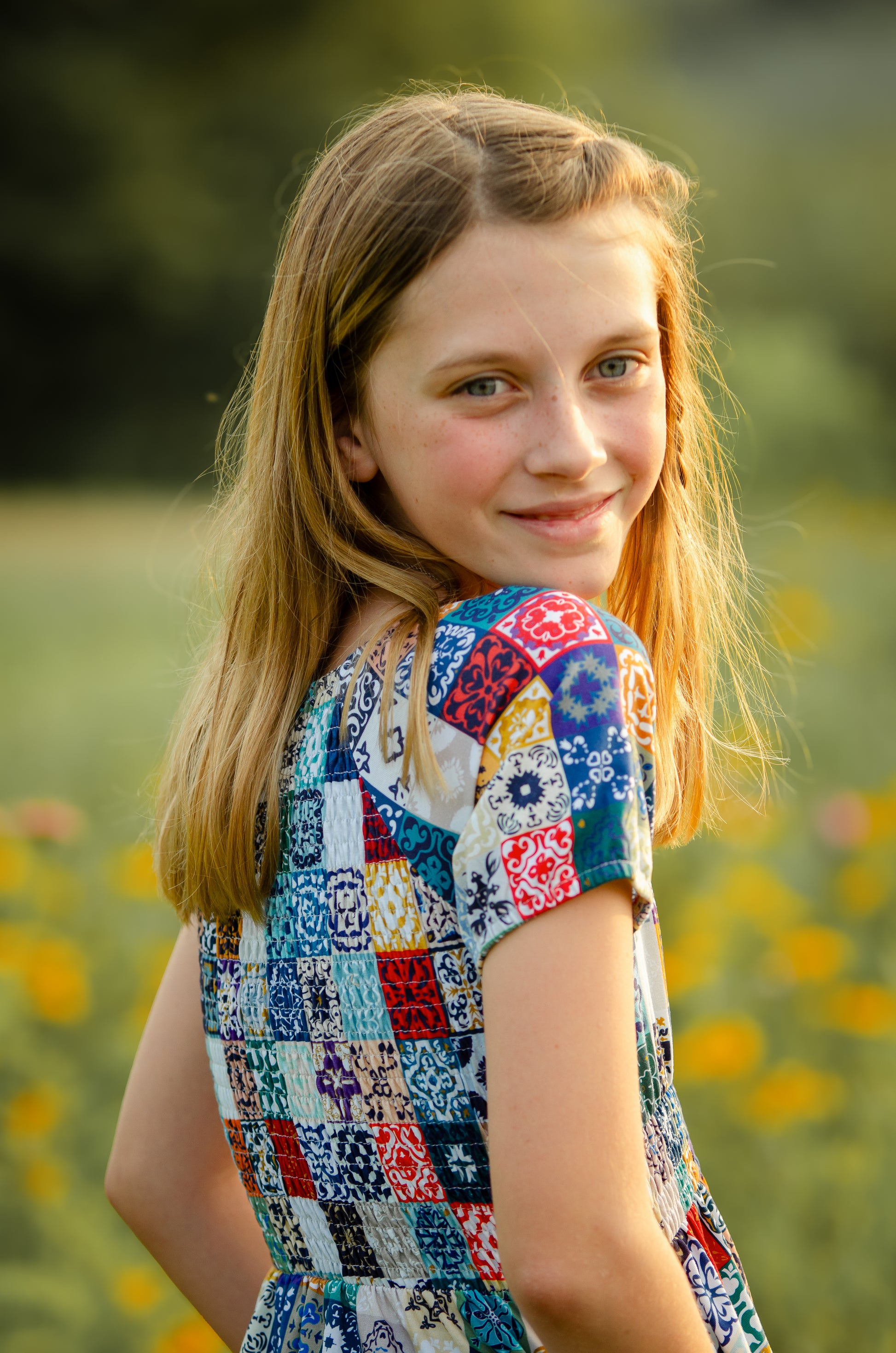 Young girl in a colorful modest dress standing in a field with flowers