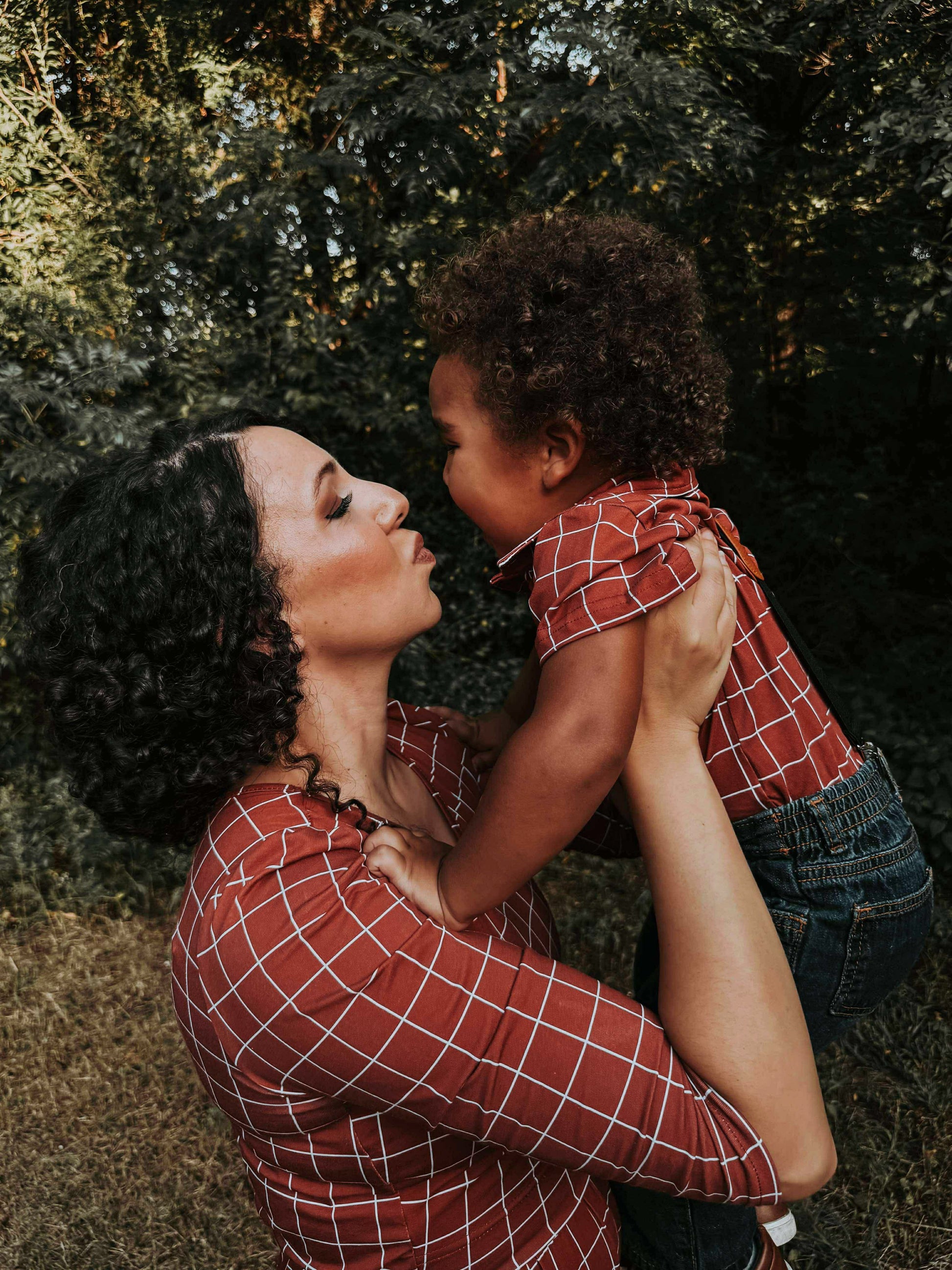 Woman holding child in park with trees