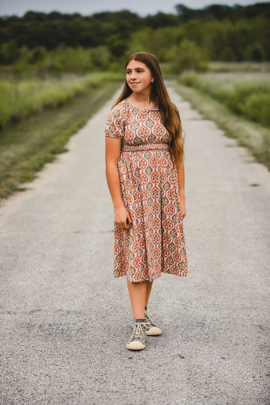 Young girl wearing colorful patterned folklore dress outdoors