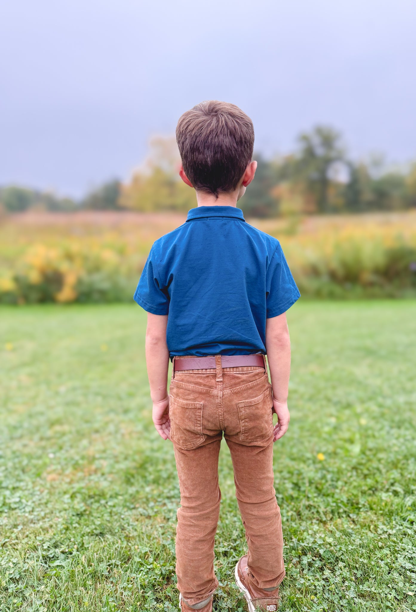 Boy wearing blue Nordic Snowdrop polo outdoors