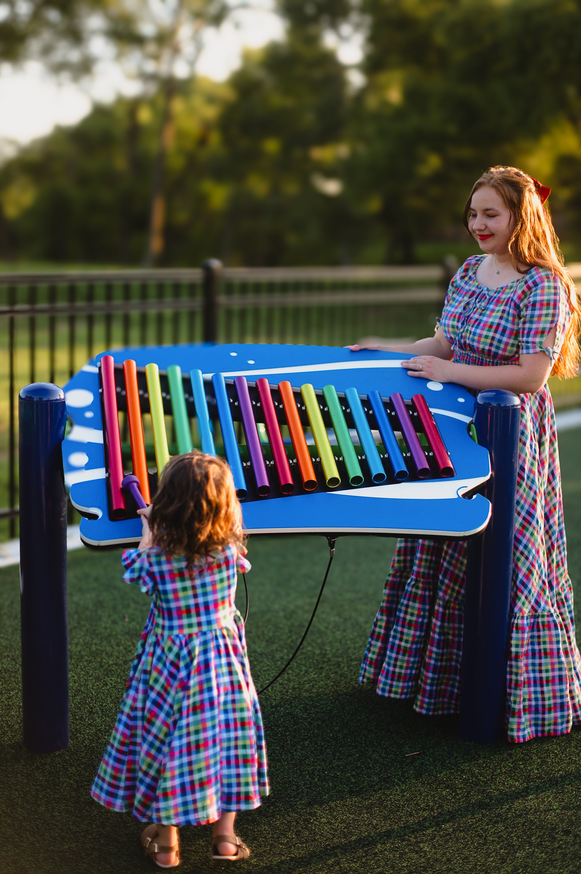 Young girl in a colorful checkered modest dress with her mother in a colorful modest nursing dress