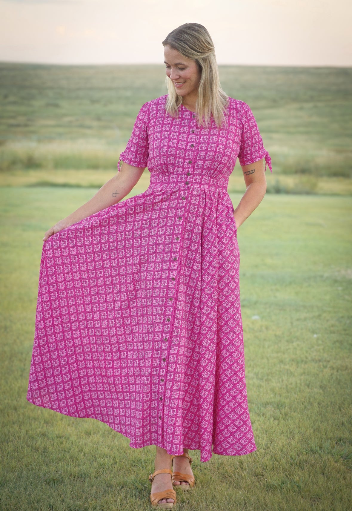 Woman in a pink modest nursing dress standing in a grassy field