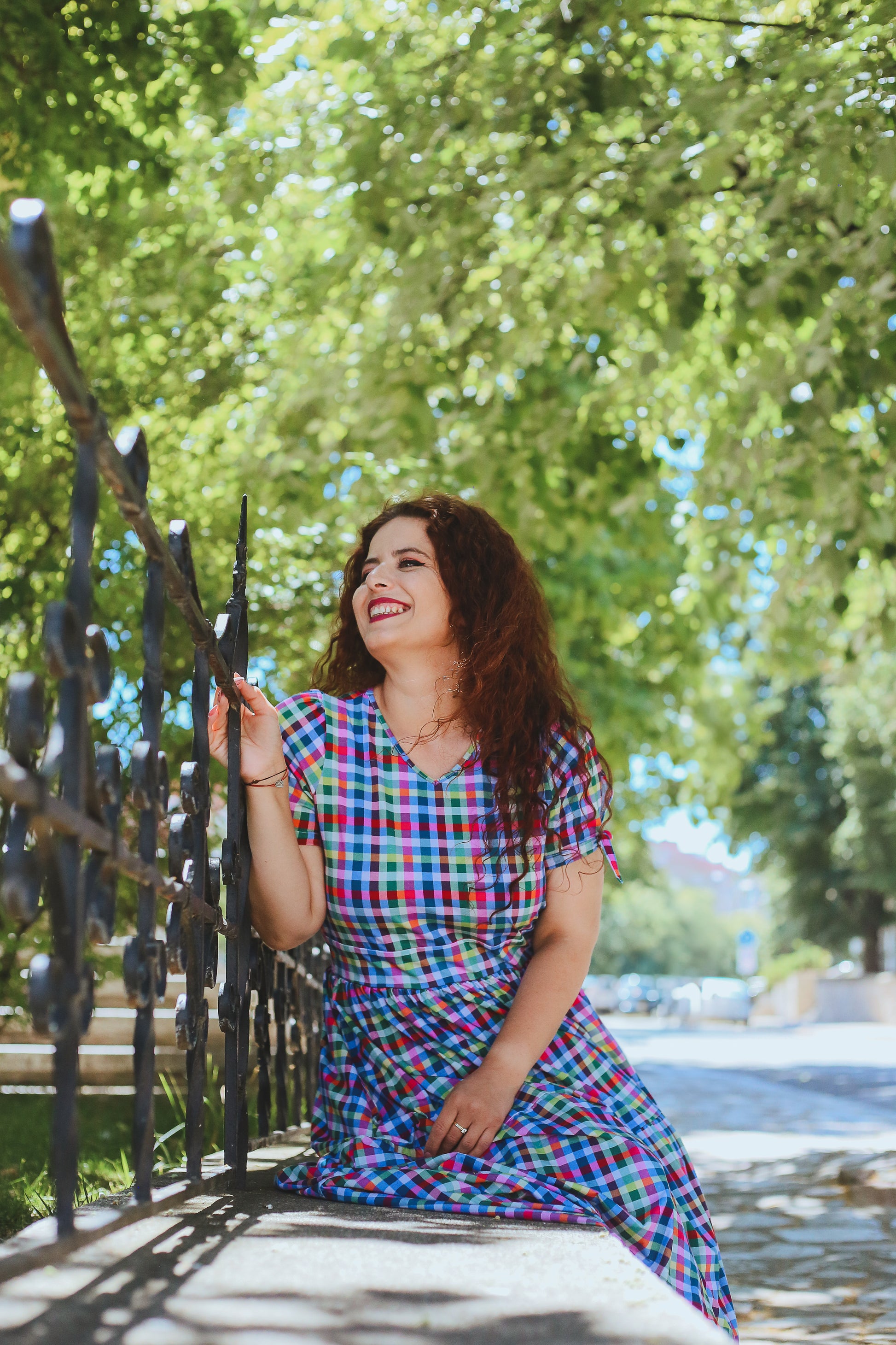Woman in a colorful modest nursing dress sitting on a bench under a tree