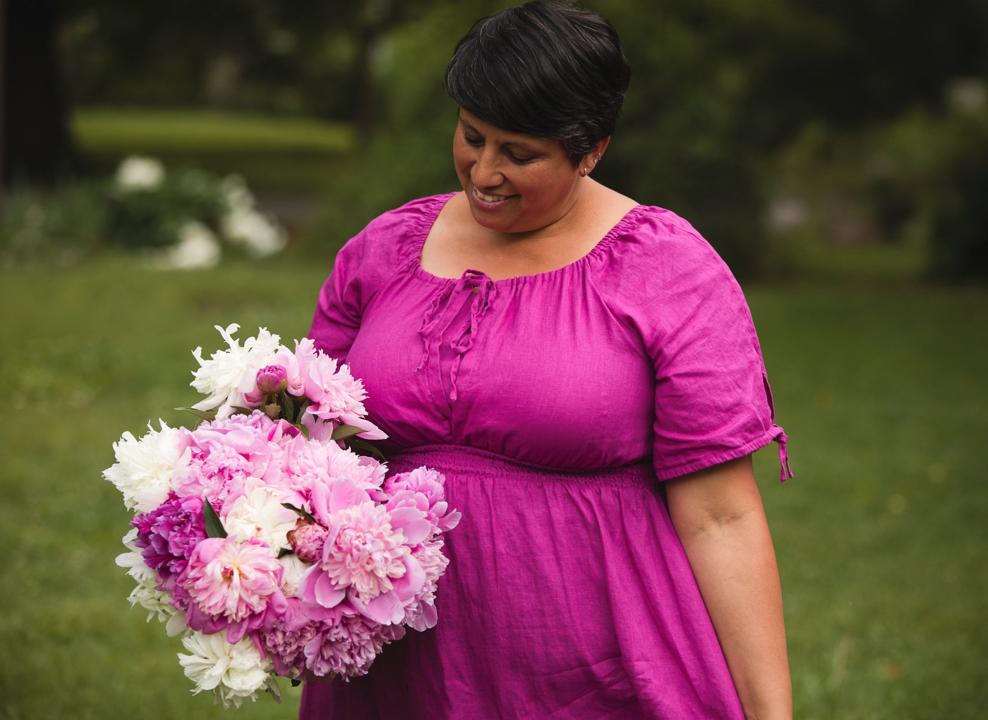 Woman in a pink modest nursing dress holding a bouquet of flowers outdoors