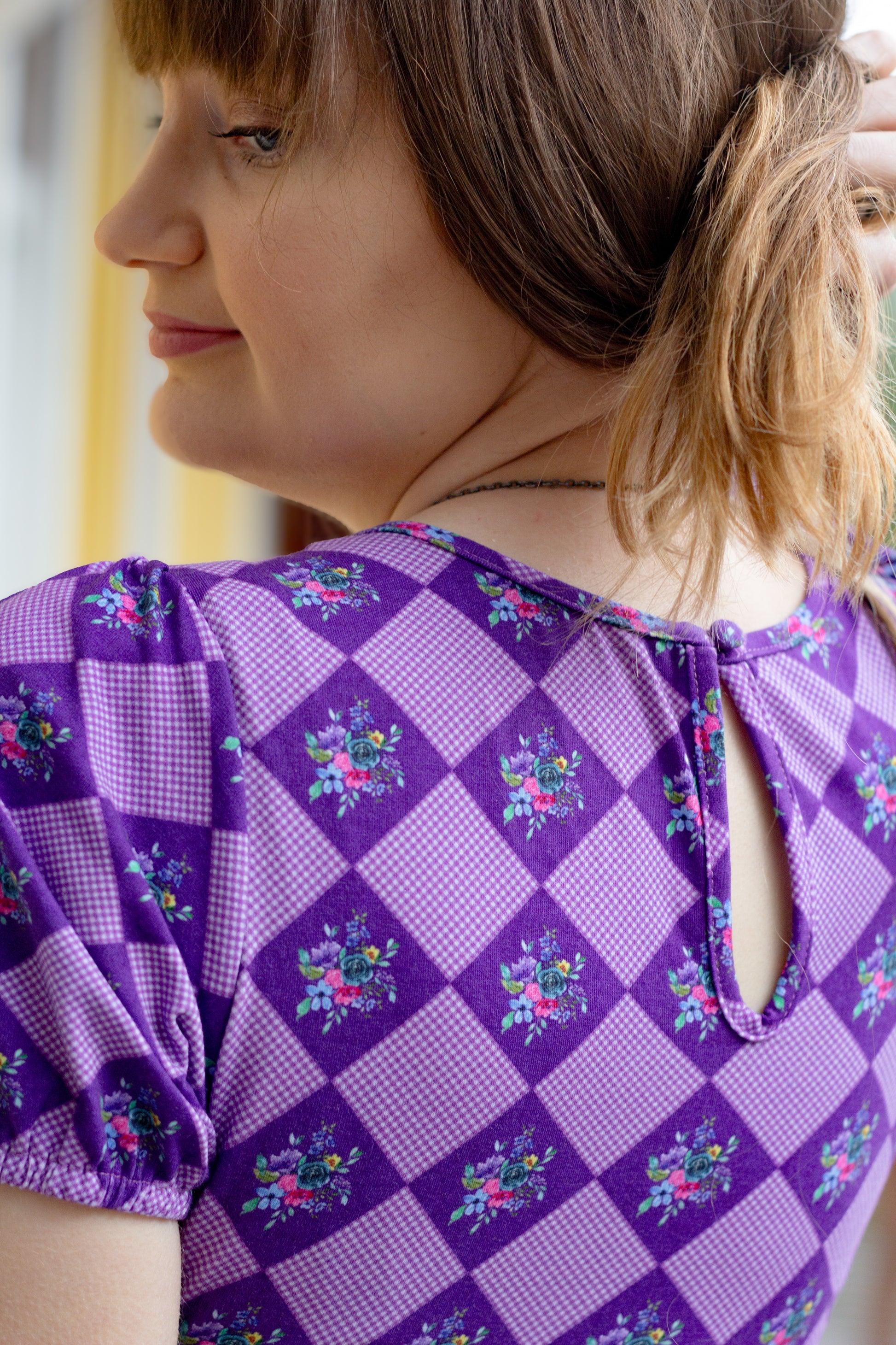 Woman in a purple checkered modest nursing dress.