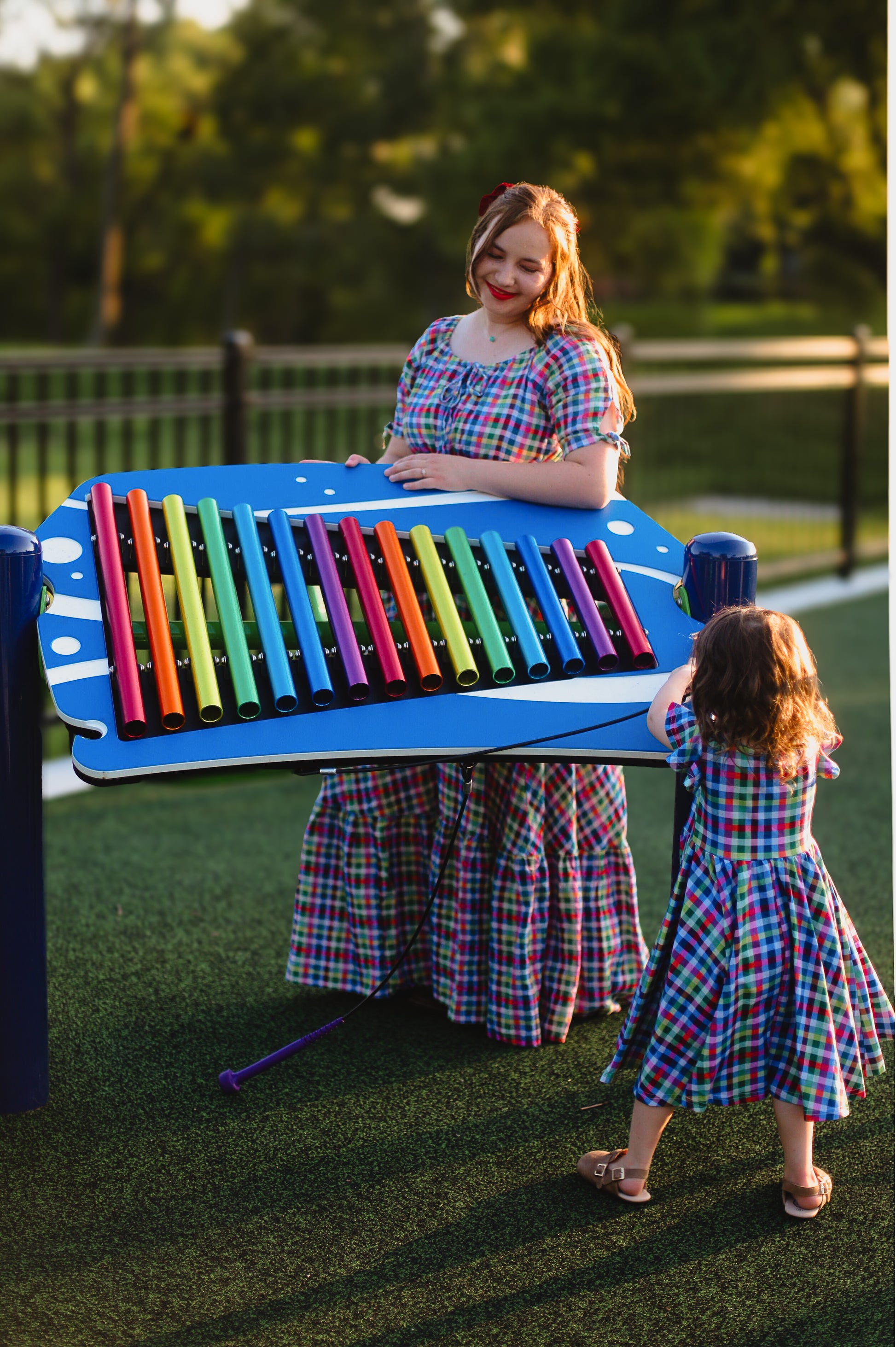 Young girl in a colorful checkered modest dress with her mother in a colorful modest nursing dress