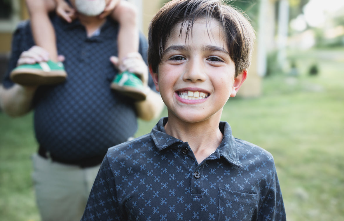 Young boys wearing dark blue polo shirts with their father in a matching shirt