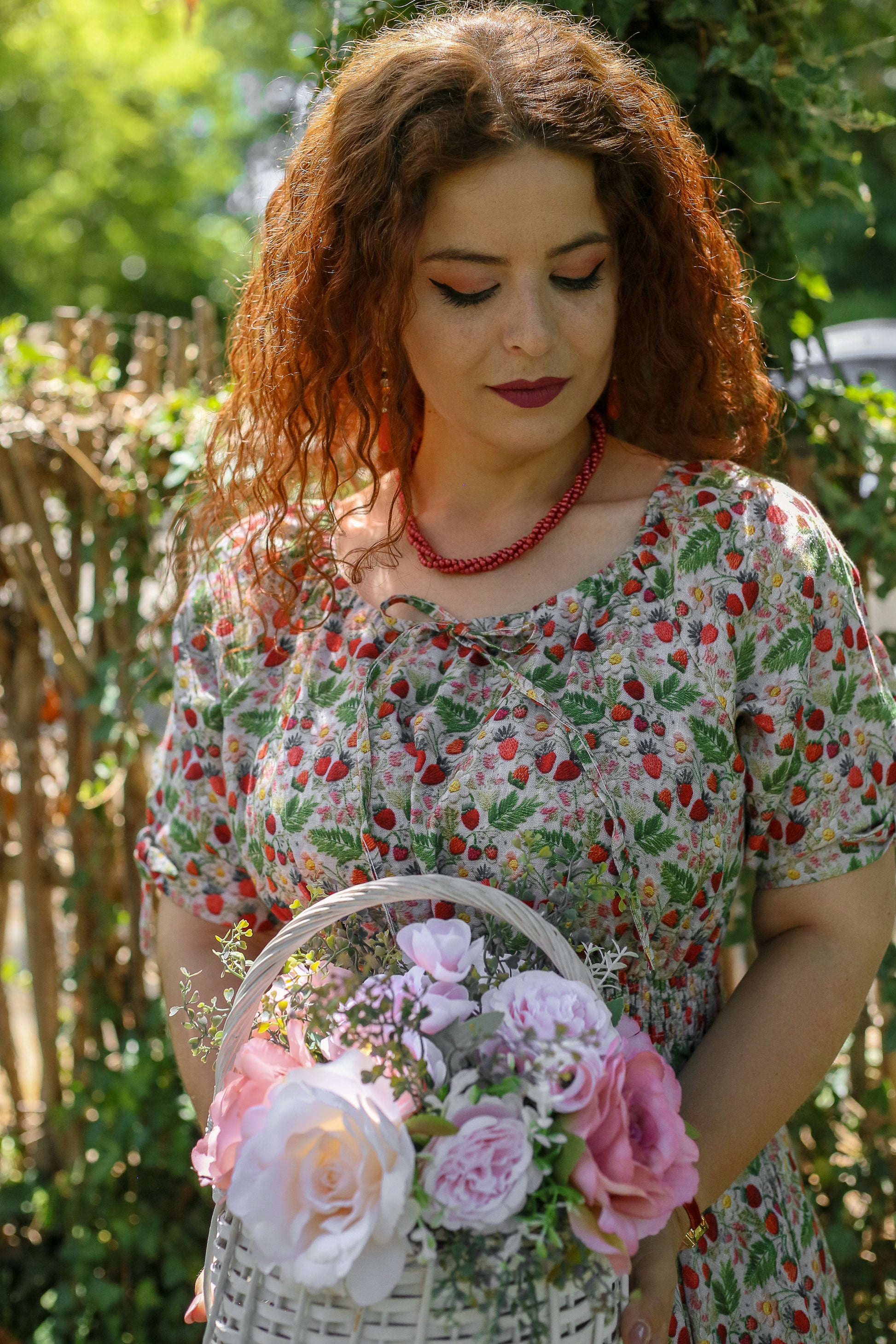 Woman holding a basket of flowers in a garden setting wearing a modest nursing dress