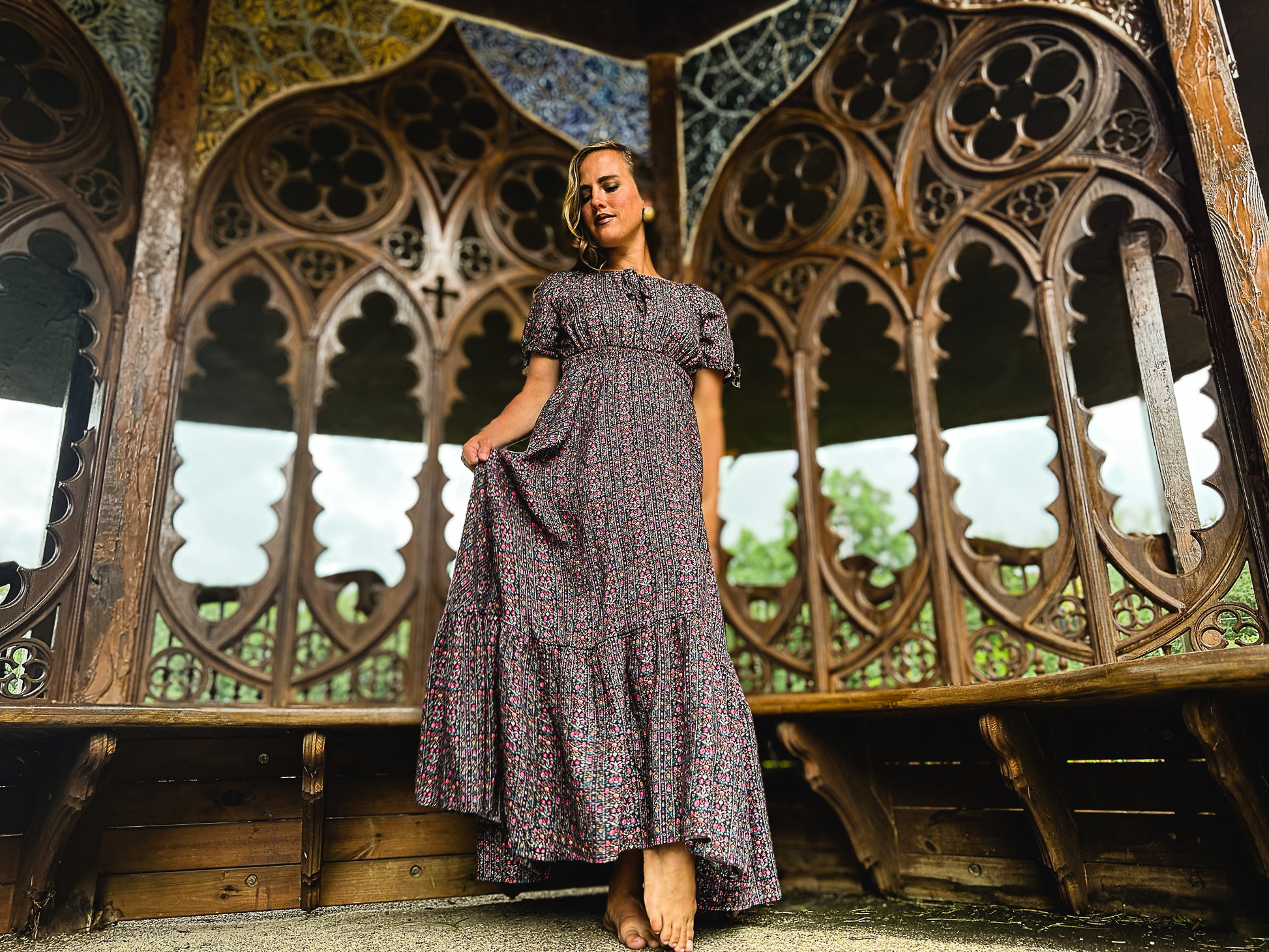 Woman in a floral modest nursing dress standing in front of ornate metalwork