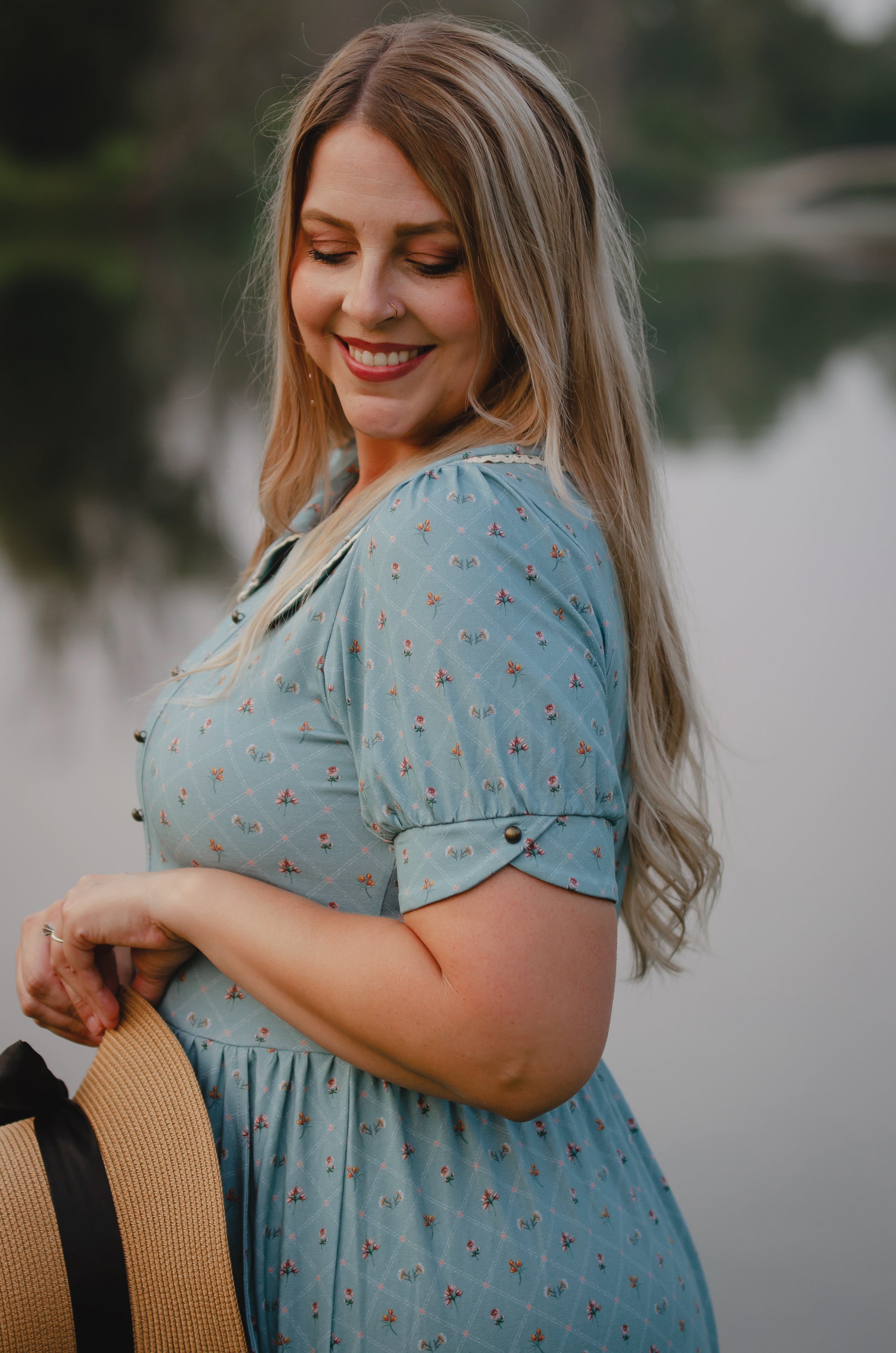 Woman in a blue modest nursing dress holding a hat outdoors