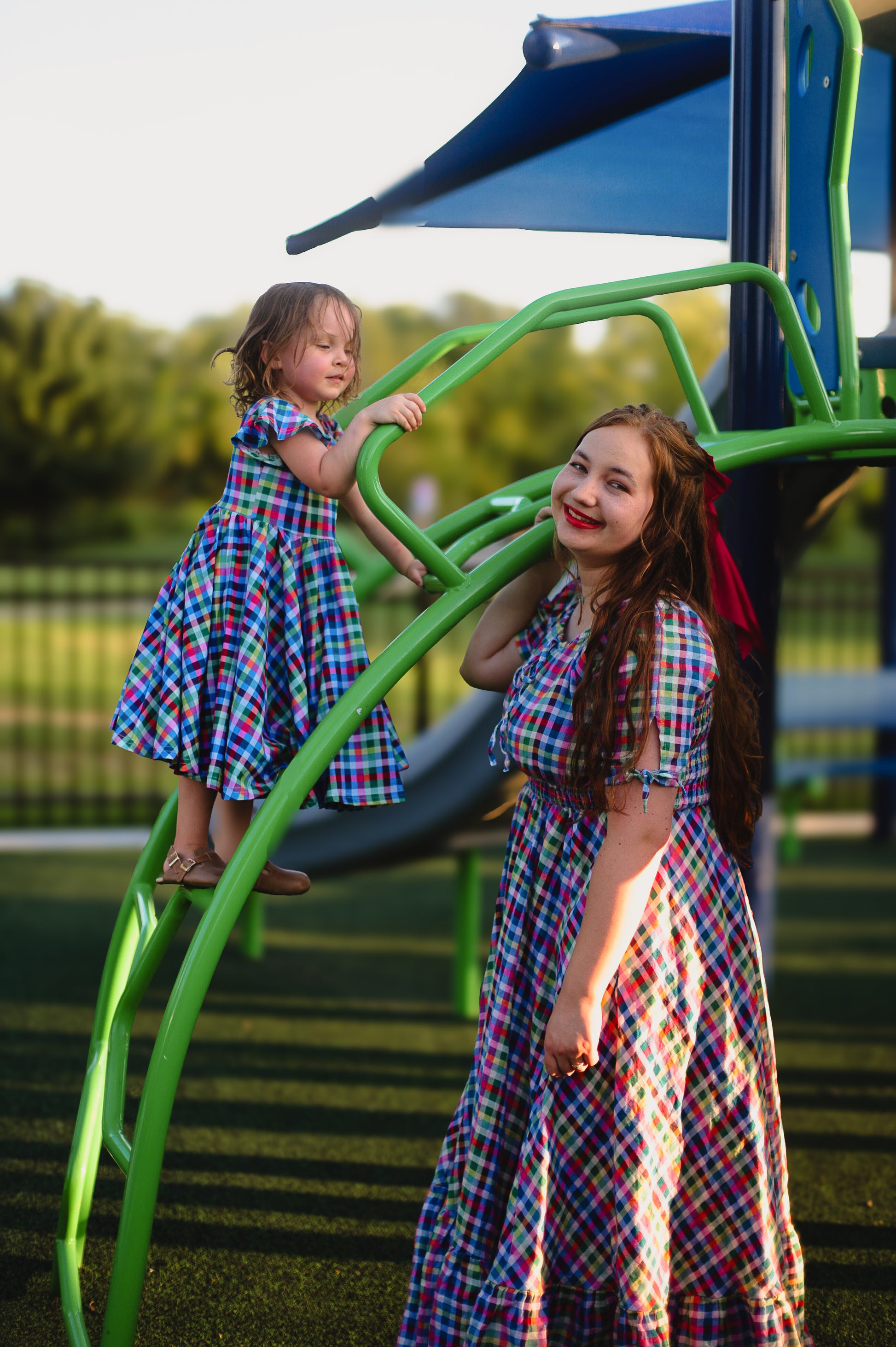 Young girl in a colorful checkered modest dress with her mother in a colorful modest nursing dress