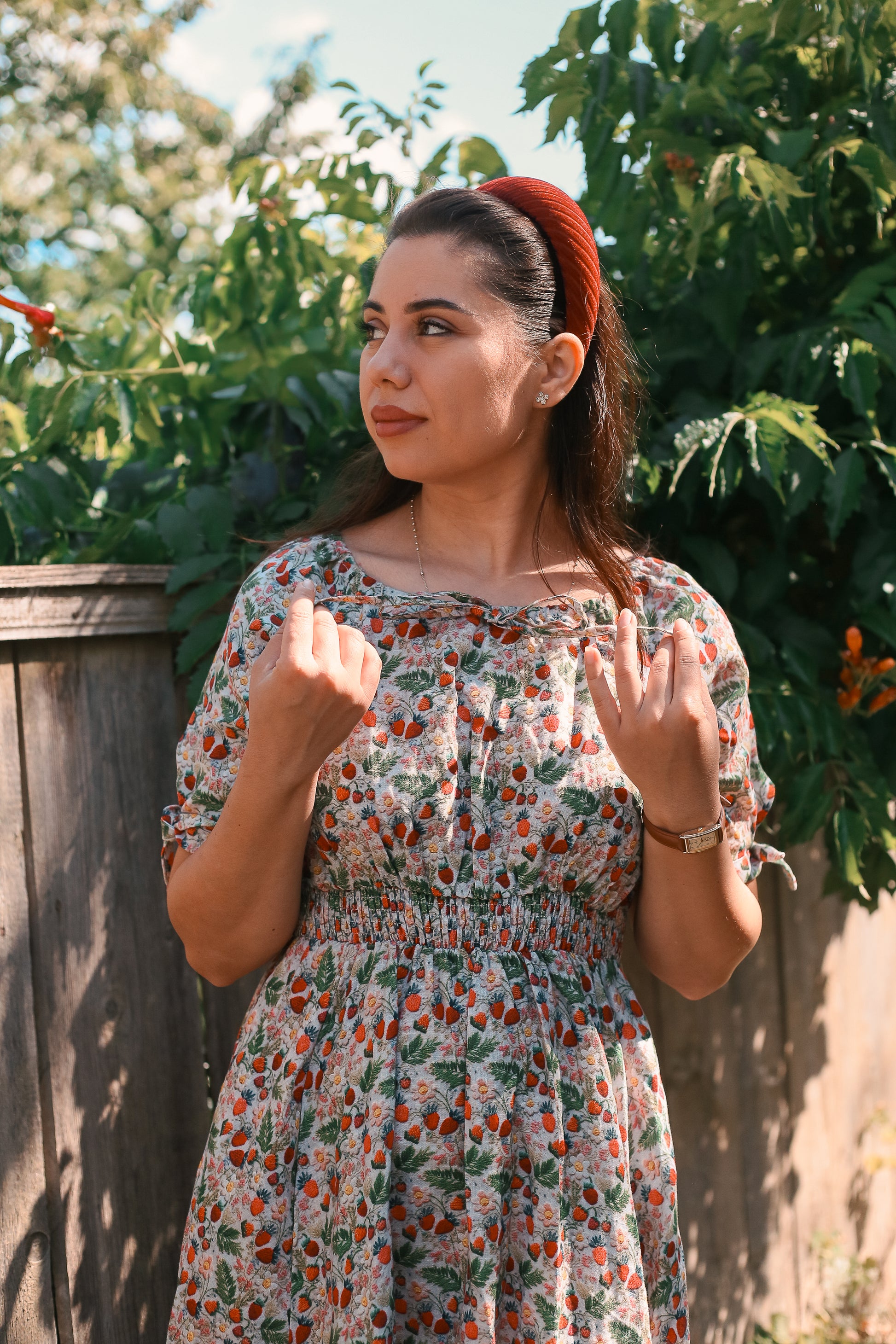 Woman in a floral modest nursing dress standing outdoors with greenery in the background
