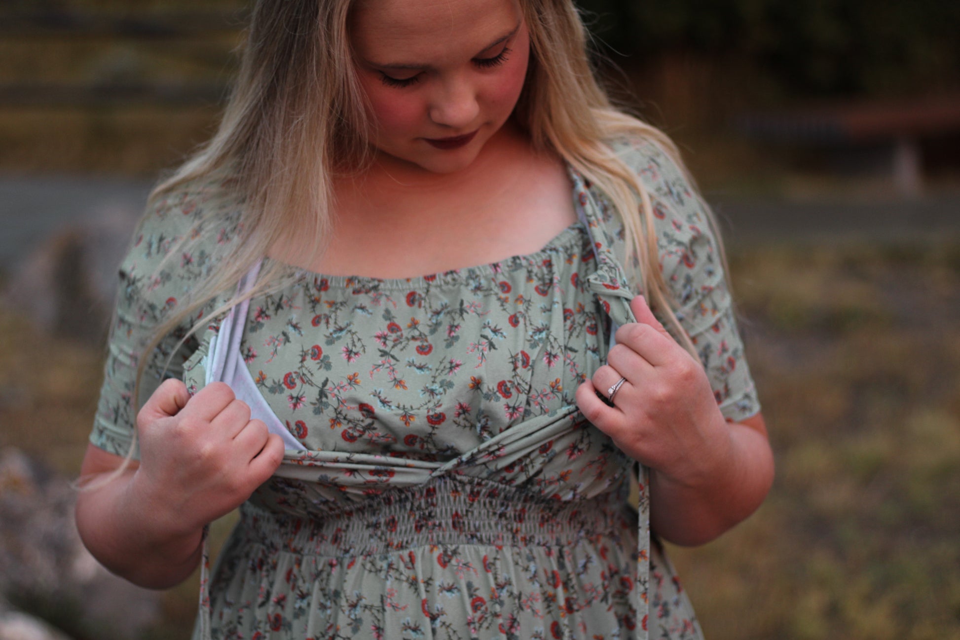 Woman in modest nursing floral dress adjusting clothing outdoors