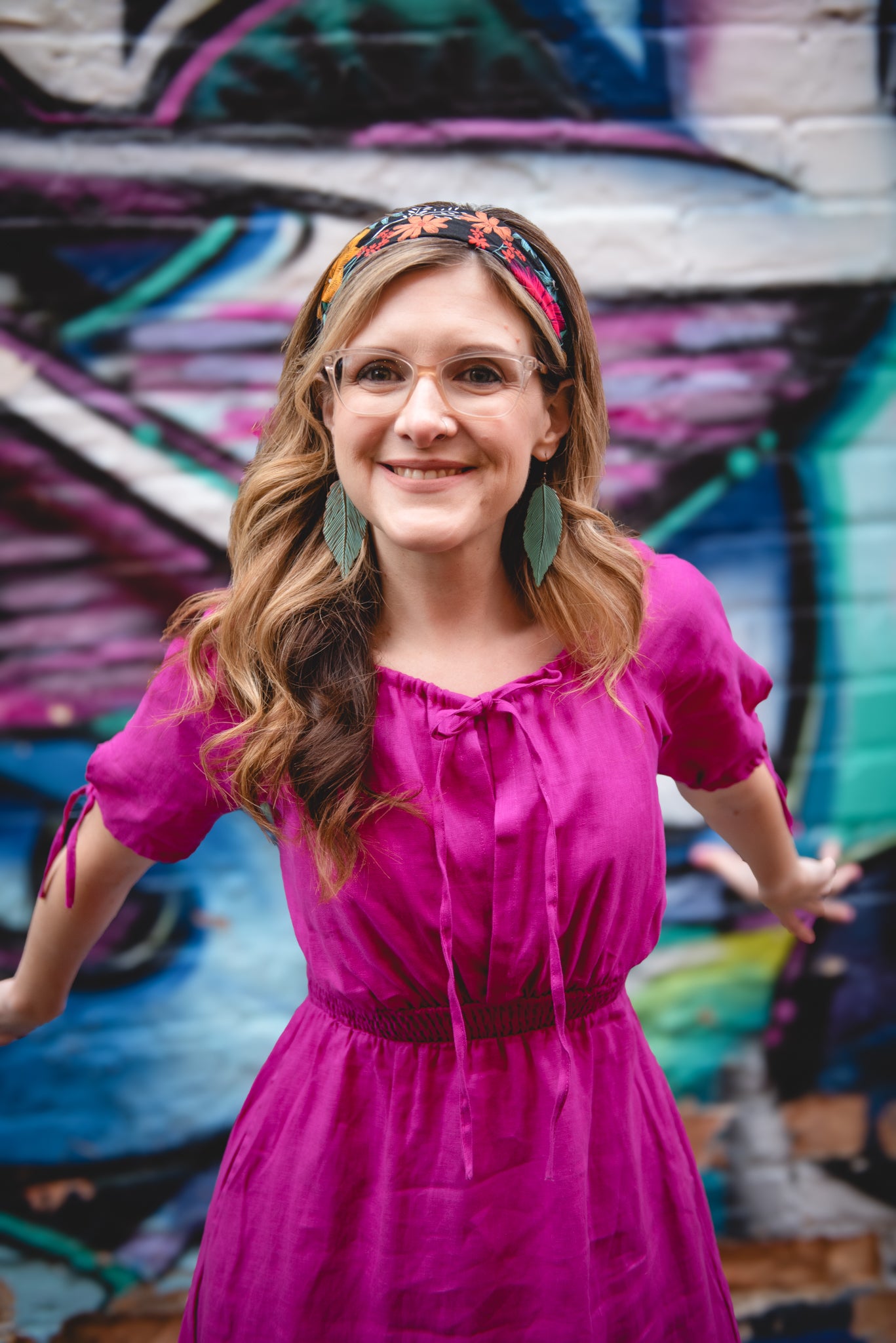 Woman in a pink modest nursing dress standing in front of colorful graffiti