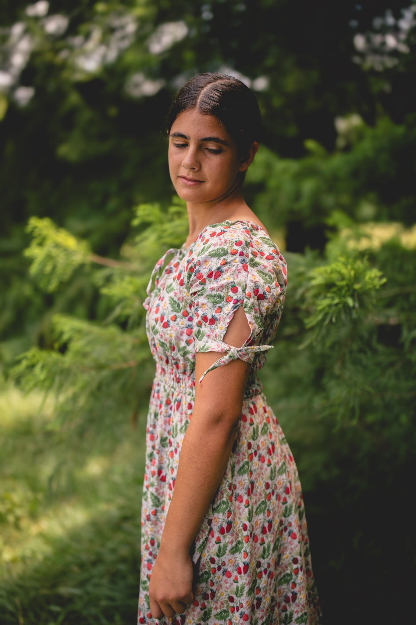 Woman in a floral modest nursing dress standing in a green, natural setting