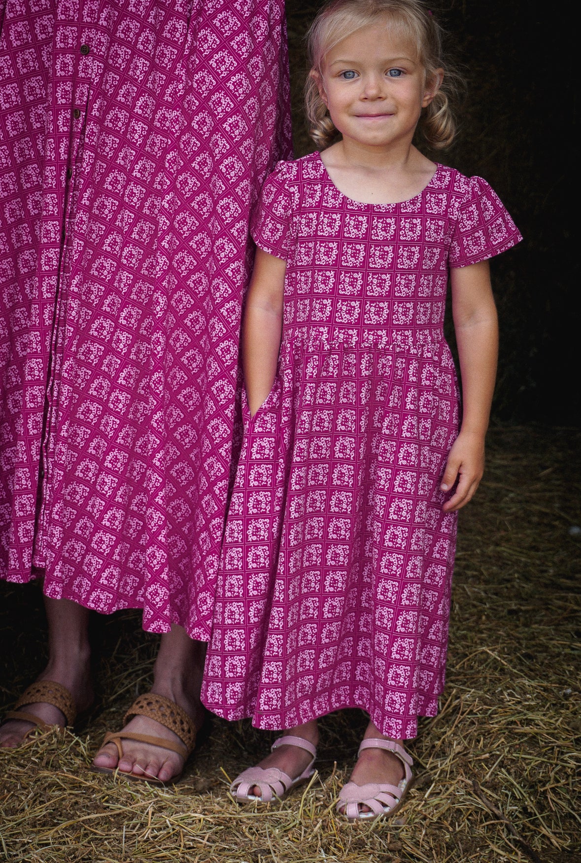 Young girl in a modest pink dress with her mother wearing a modest pink nursing dress