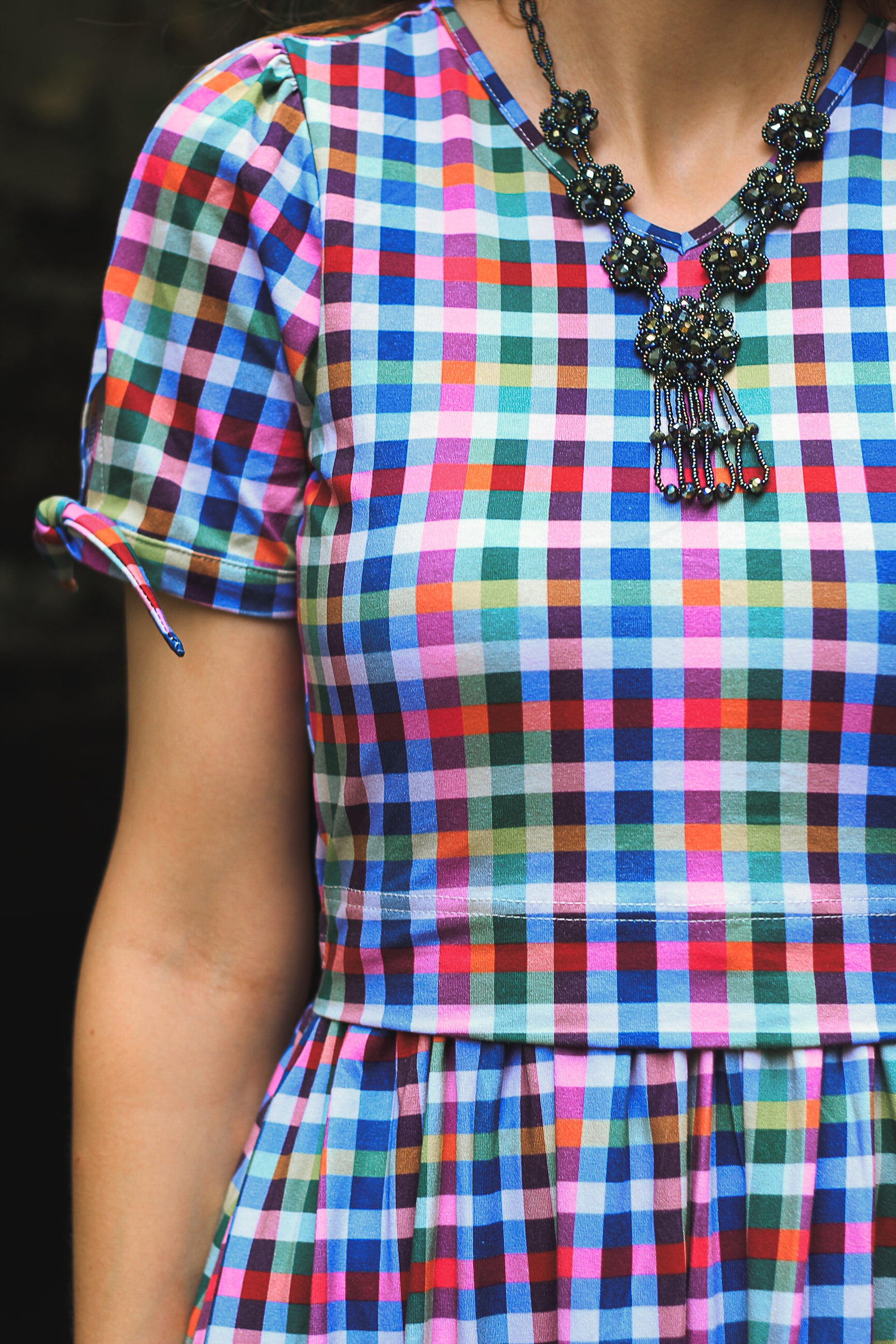 Multicolored checkered modest nursing dress with a black necklace on a dark background