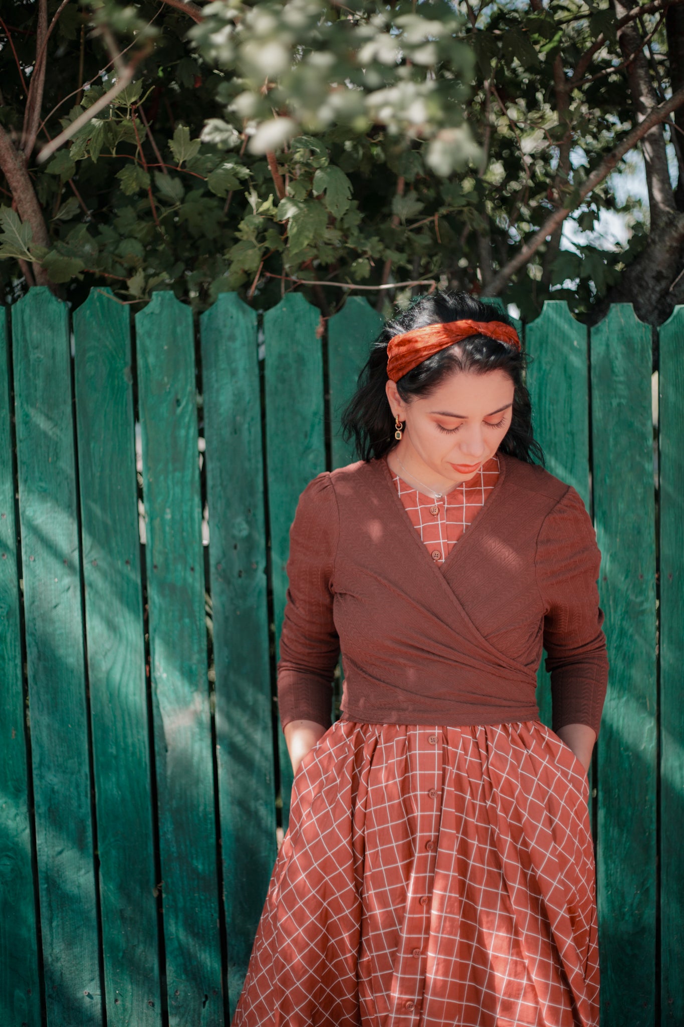 Woman in modest nursing red plaid skirt fence