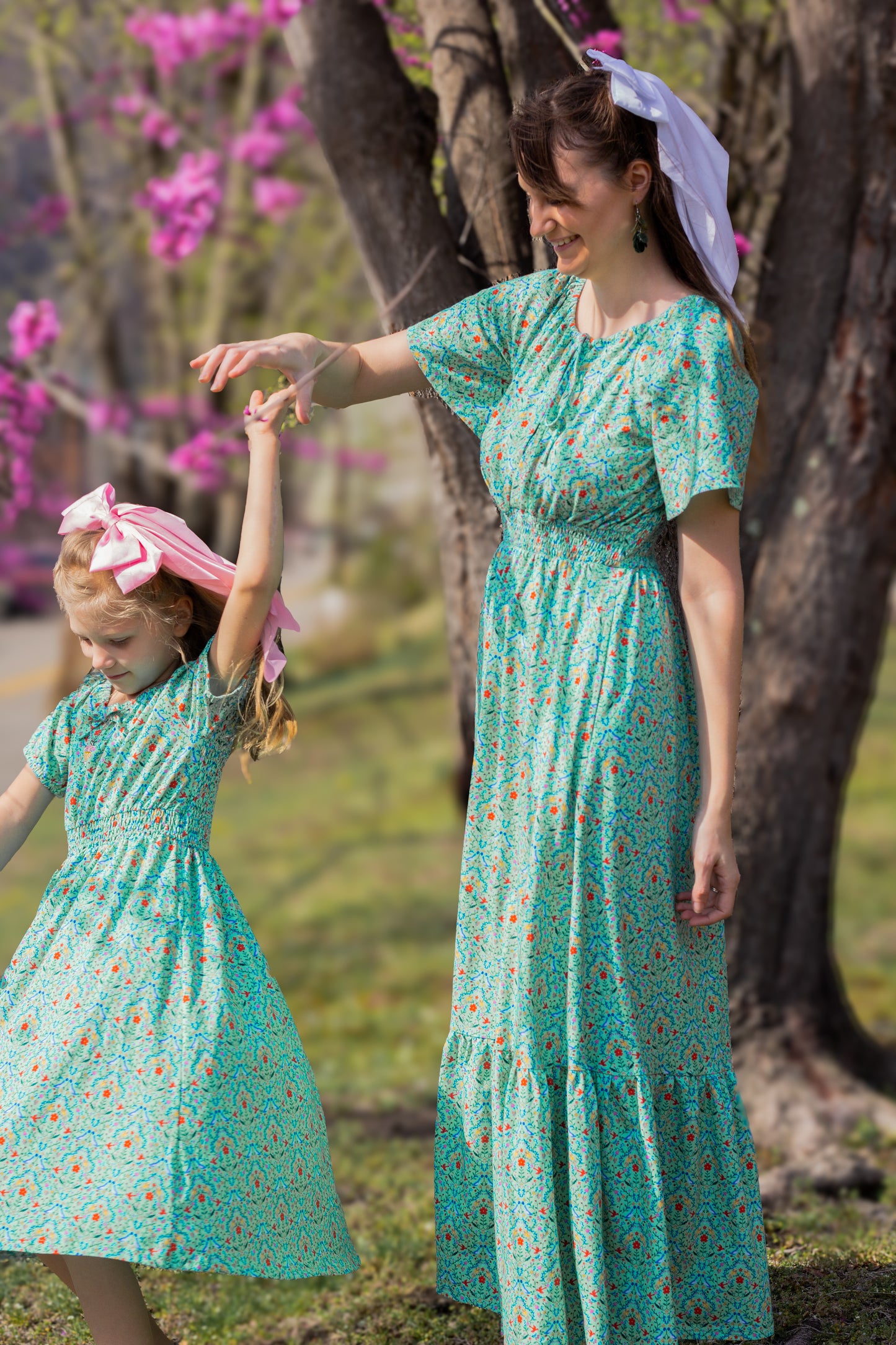 Young girl wearing a modest green dress with her mother in a modest green nursing dress