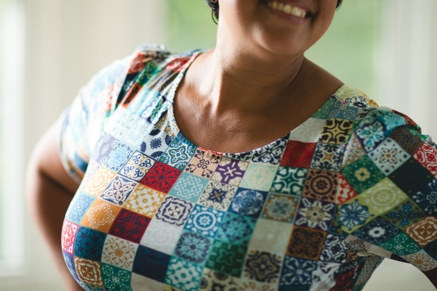 Person wearing a colorful patchwork modest nursing dress with a blurred background