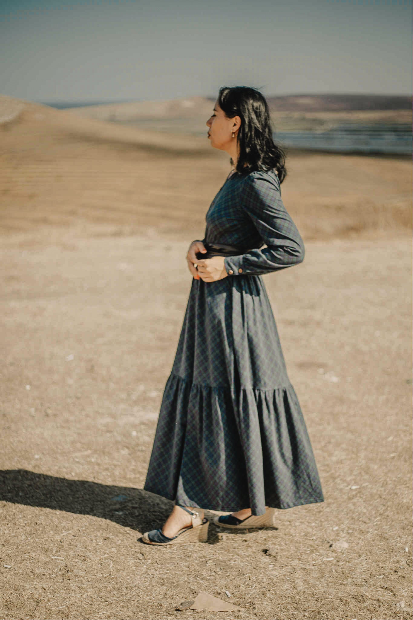 Woman in modest nursing dark dress desert landscape