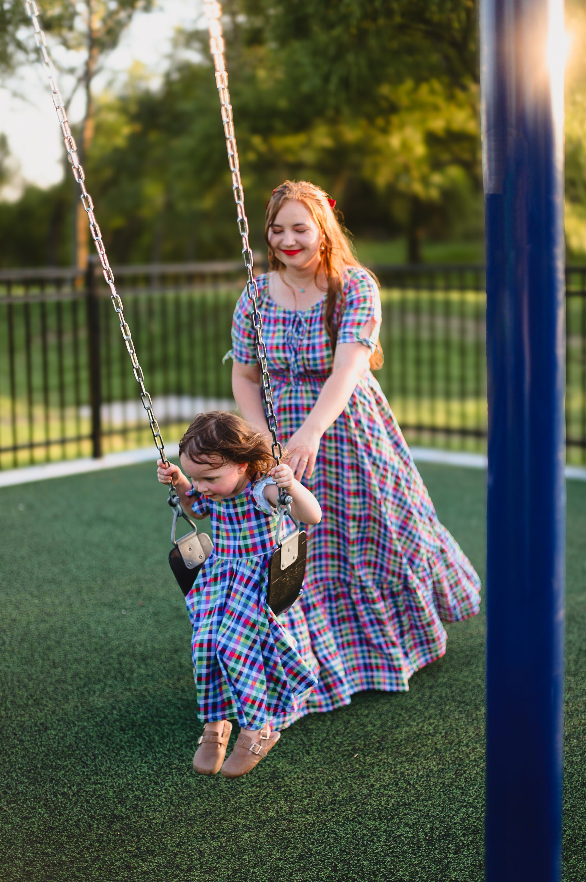 Young girl in a colorful checkered modest dress with her mother in a colorful modest nursing dress