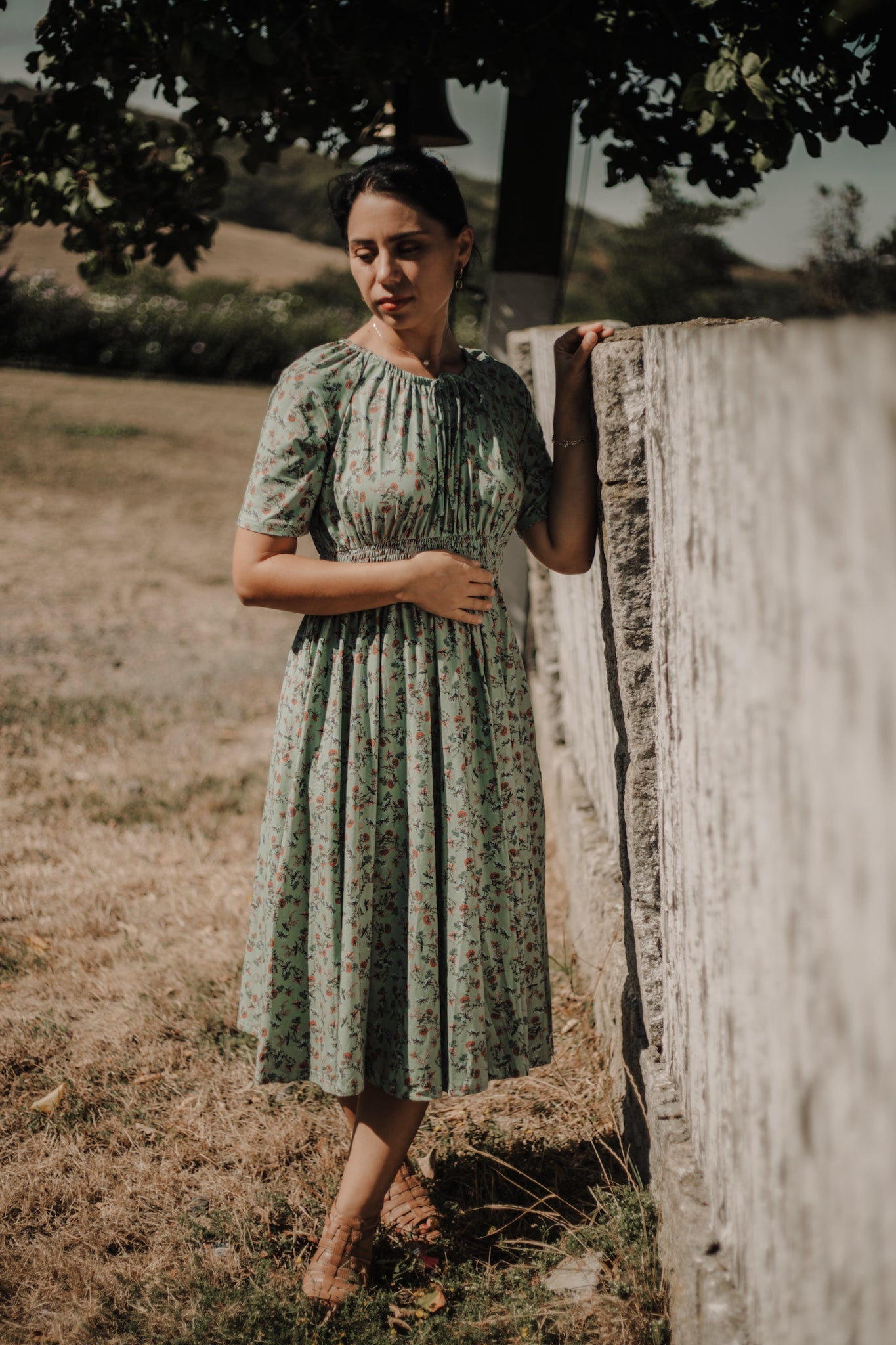 Woman in modest nursing floral dress by fence