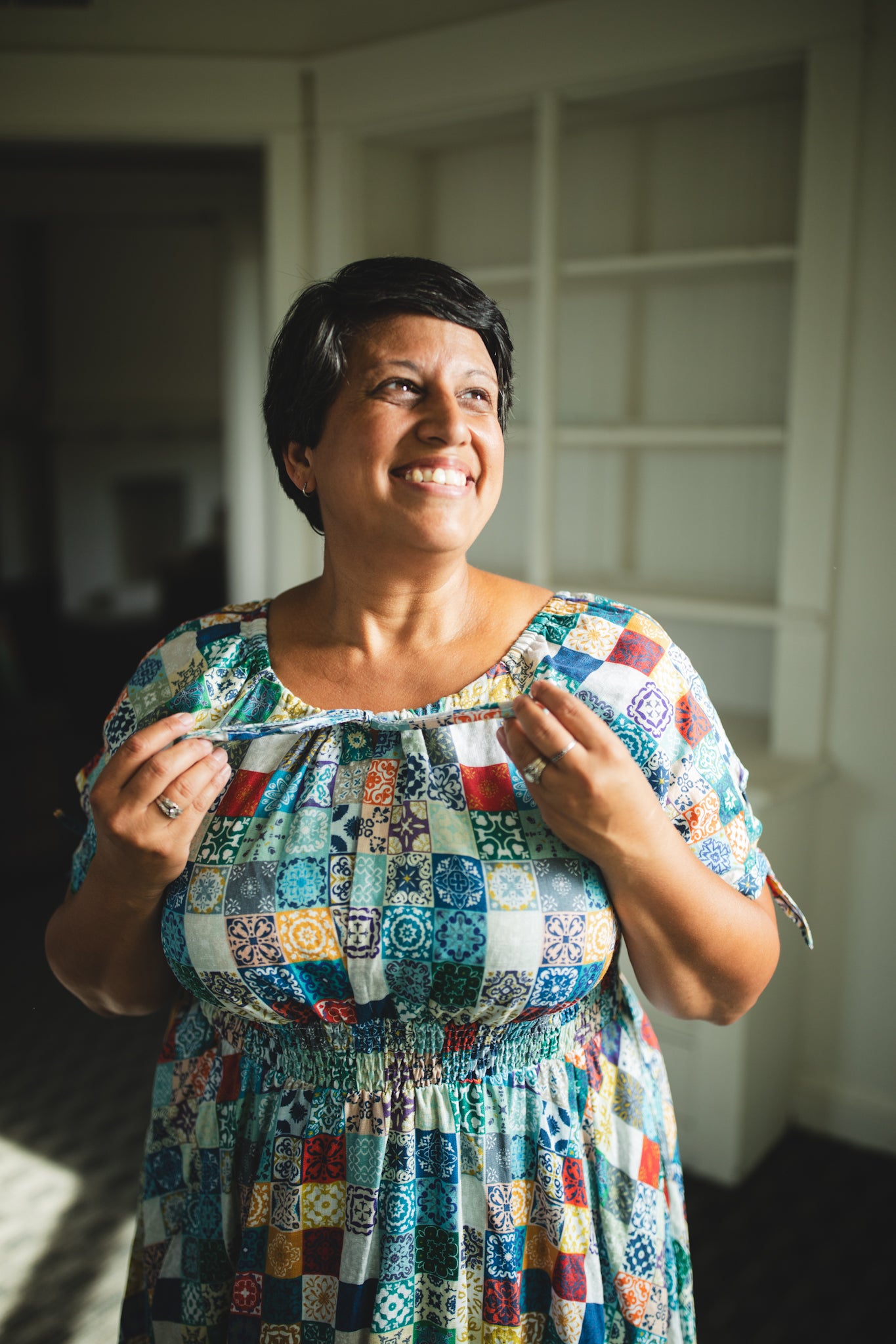 Woman wearing a colorful patchwork modest nursing dress indoors