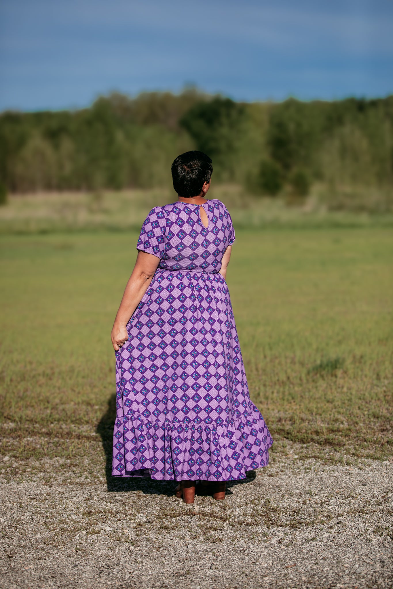 Person in a purple patterned modest nursing dress standing in a field.