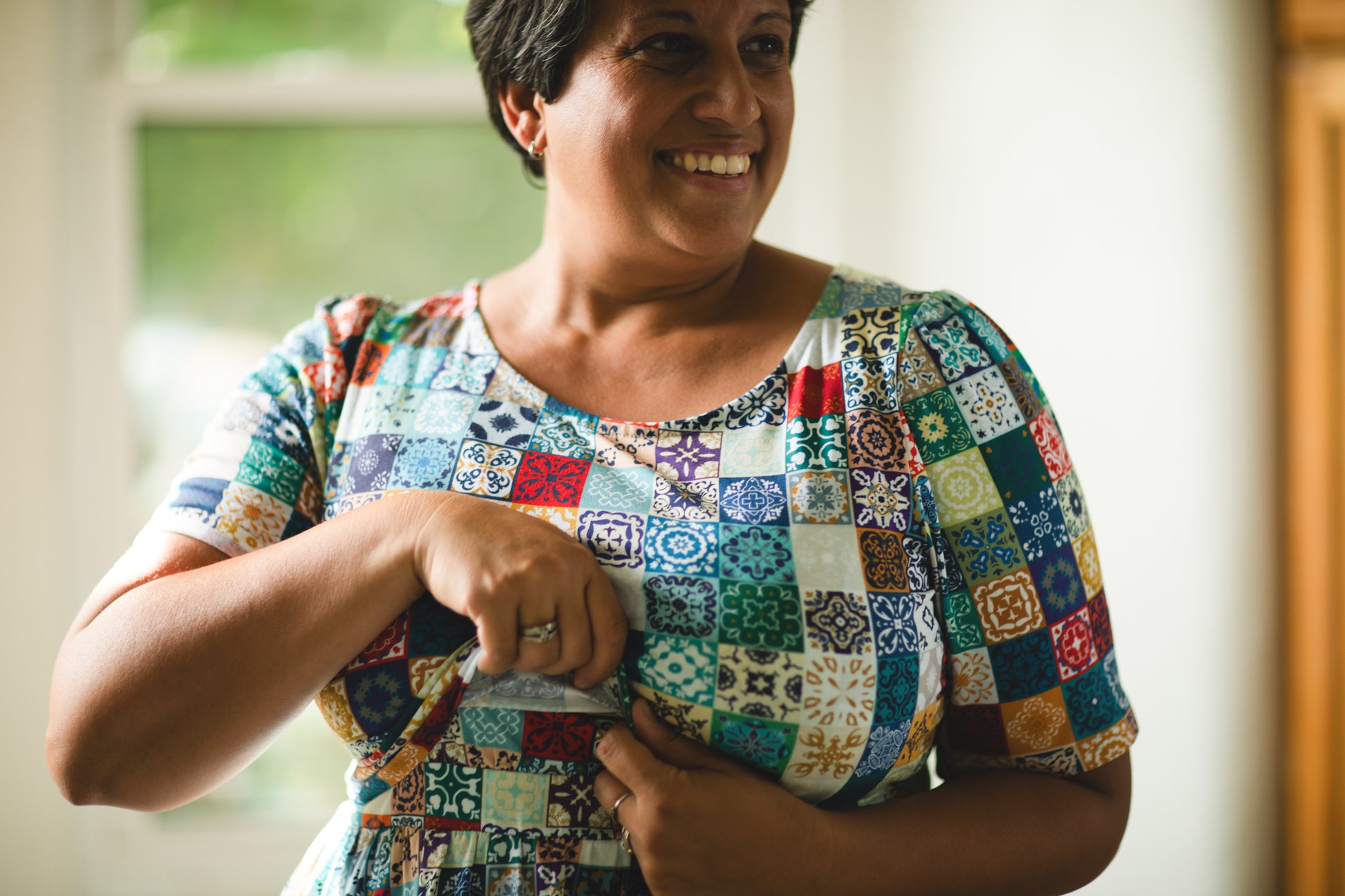 Woman wearing a colorful patchwork modest nursing dress indoors
