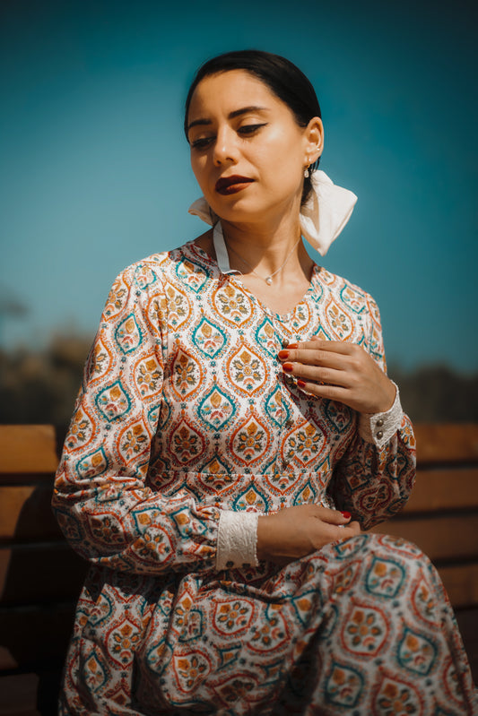 Woman wearing a patterned dress with a blurred outdoor background