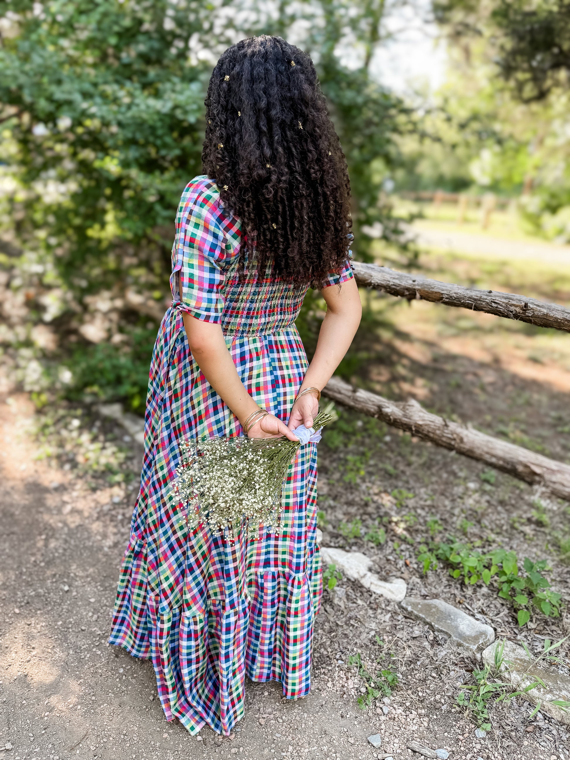 Person wearing a colorful modest nursing dress standing outdoors with greenery in the background