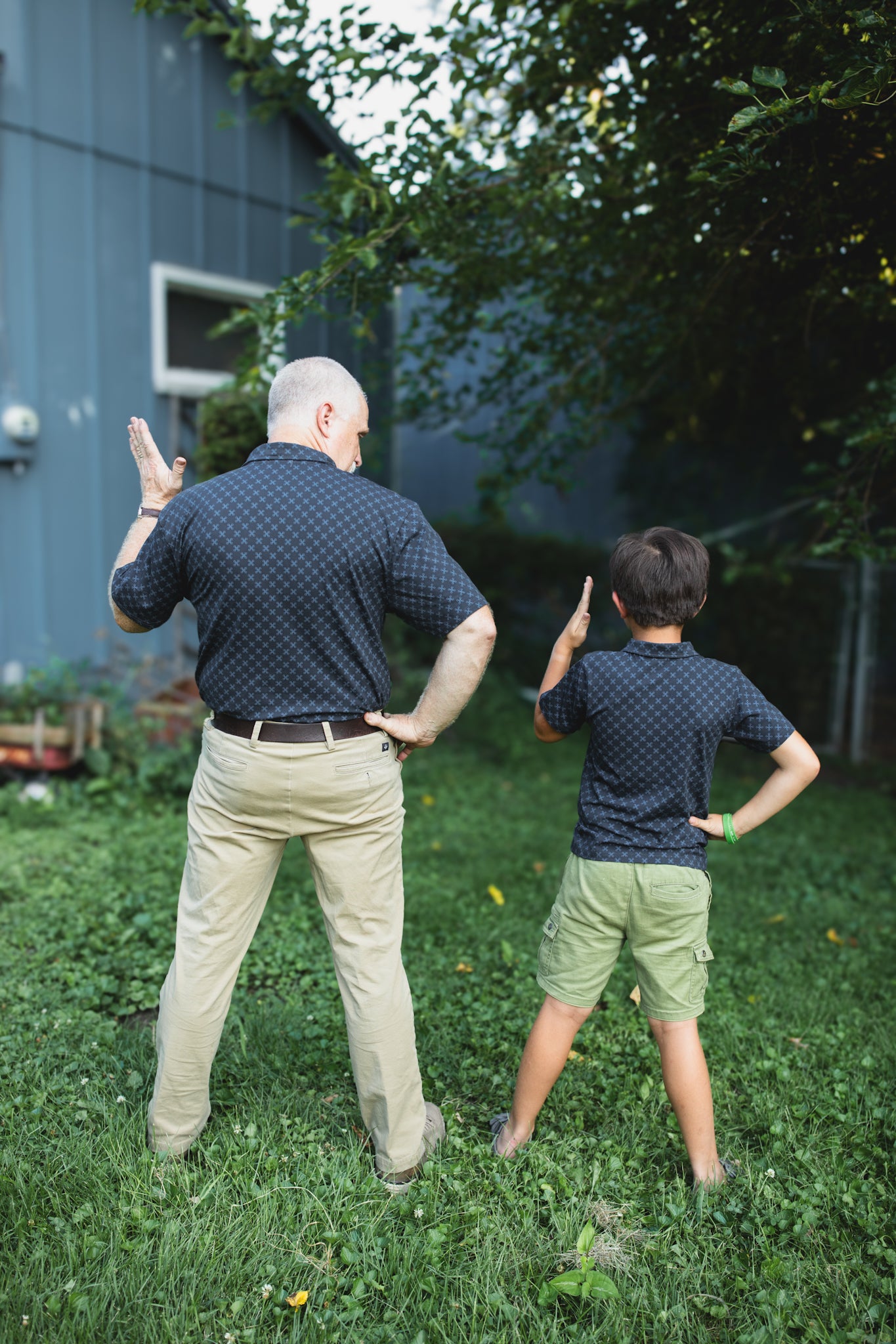 Young boy wearing a dark blue polo shirt with his father in a matching shirt