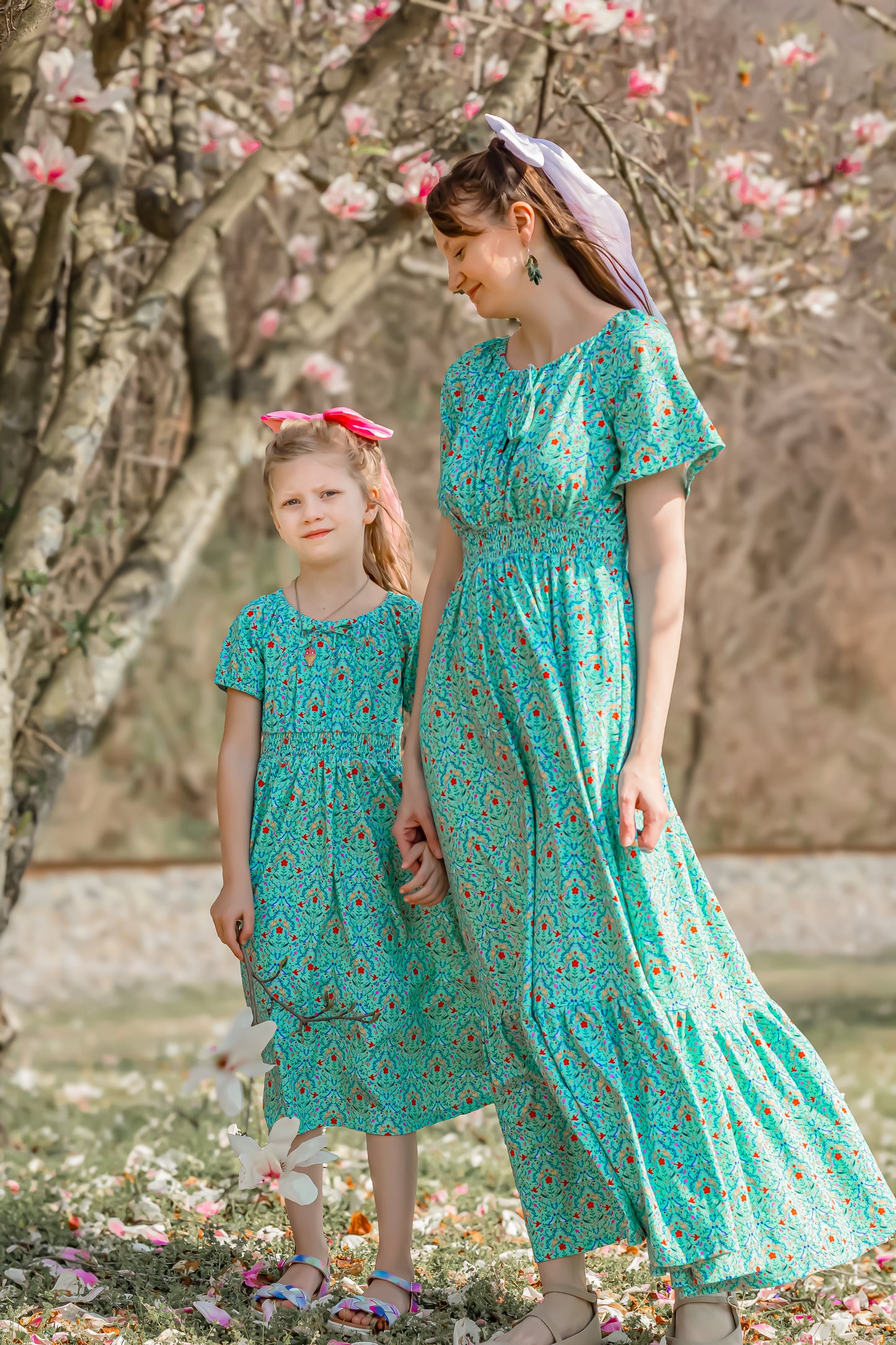Young girl wearing a modest green dress with her mother in a modest green nursing dress