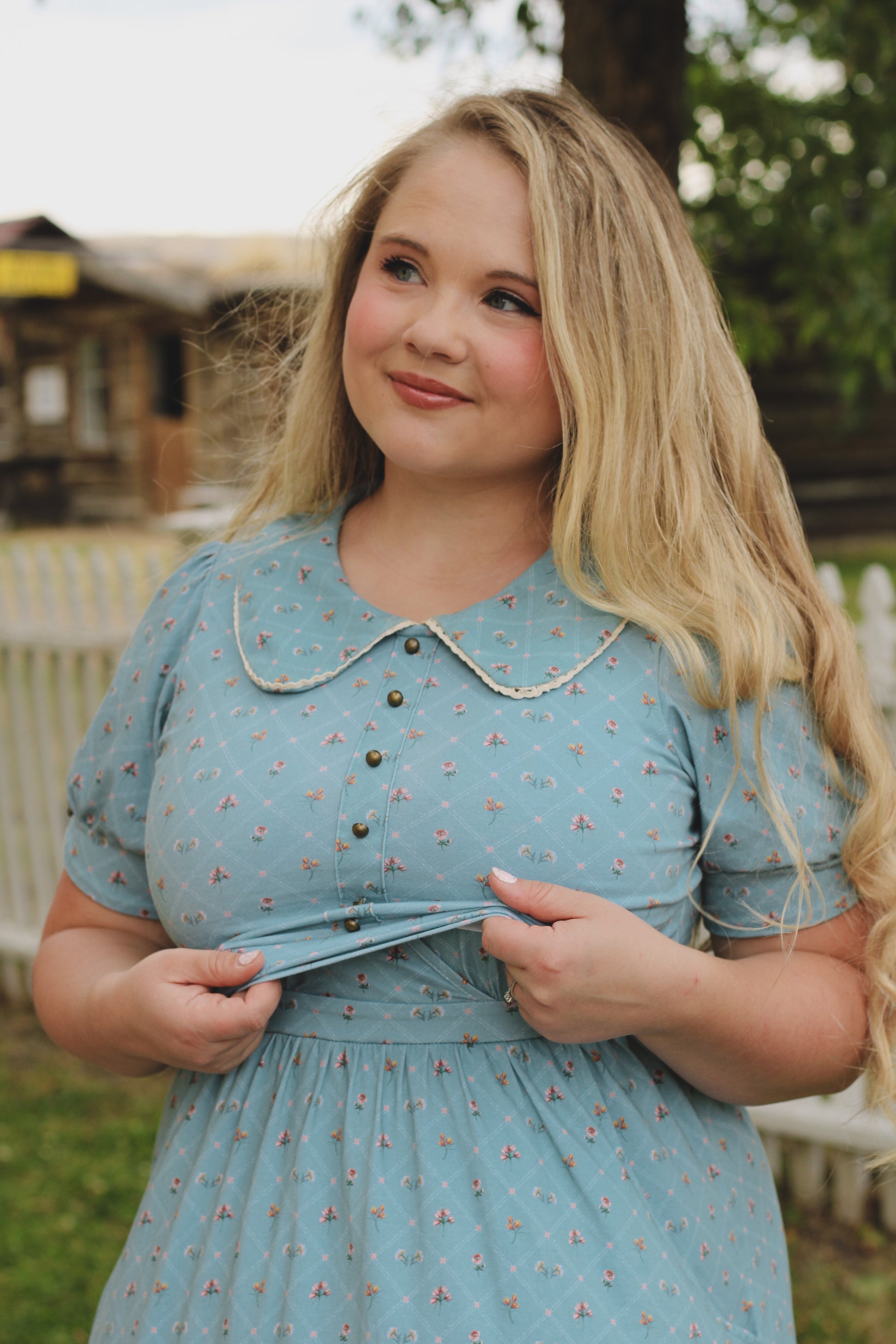 Woman wearing a blue modest nursing dress with a floral pattern outdoors