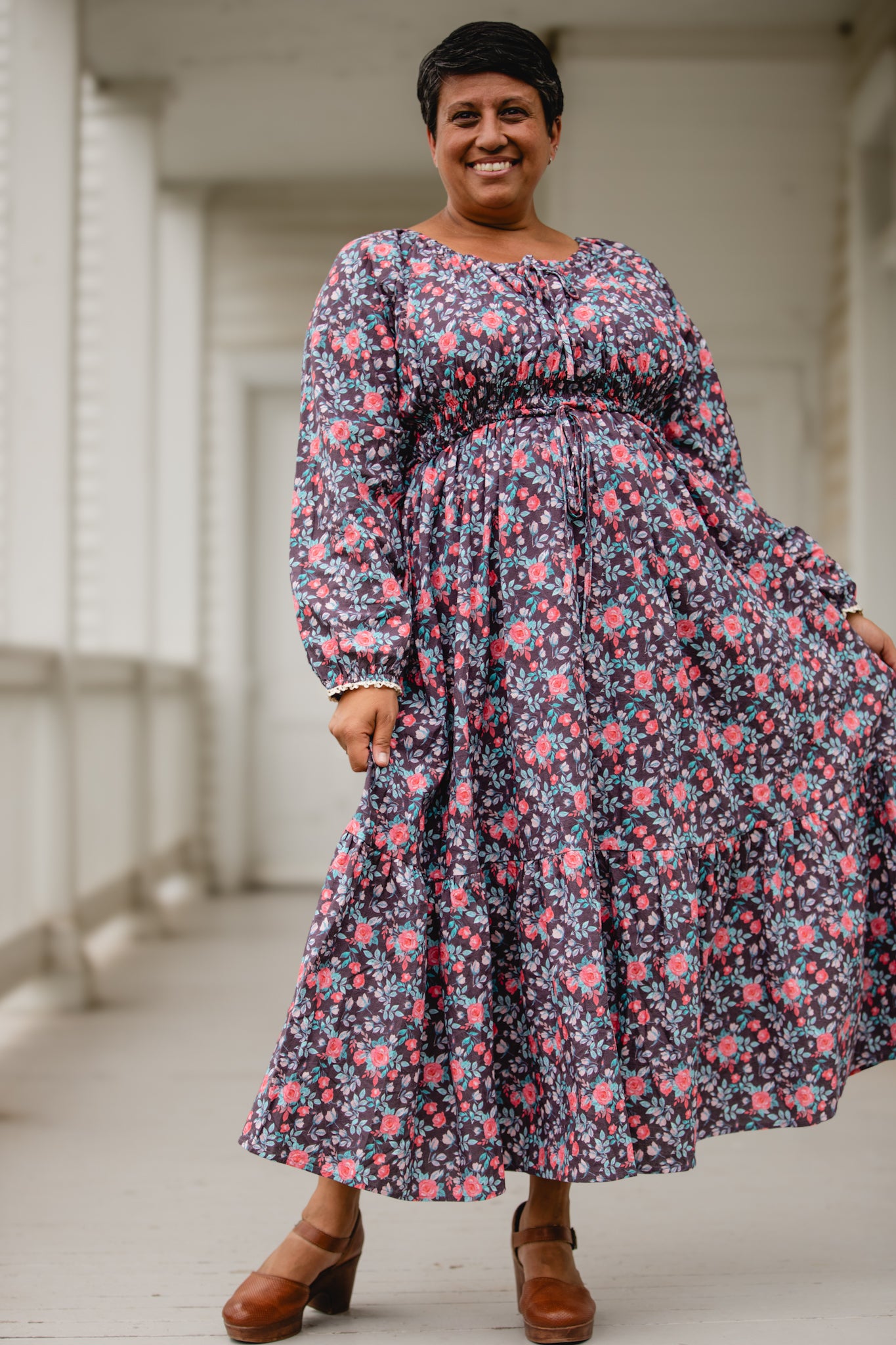 Woman in modest nursing floral dress on porch.