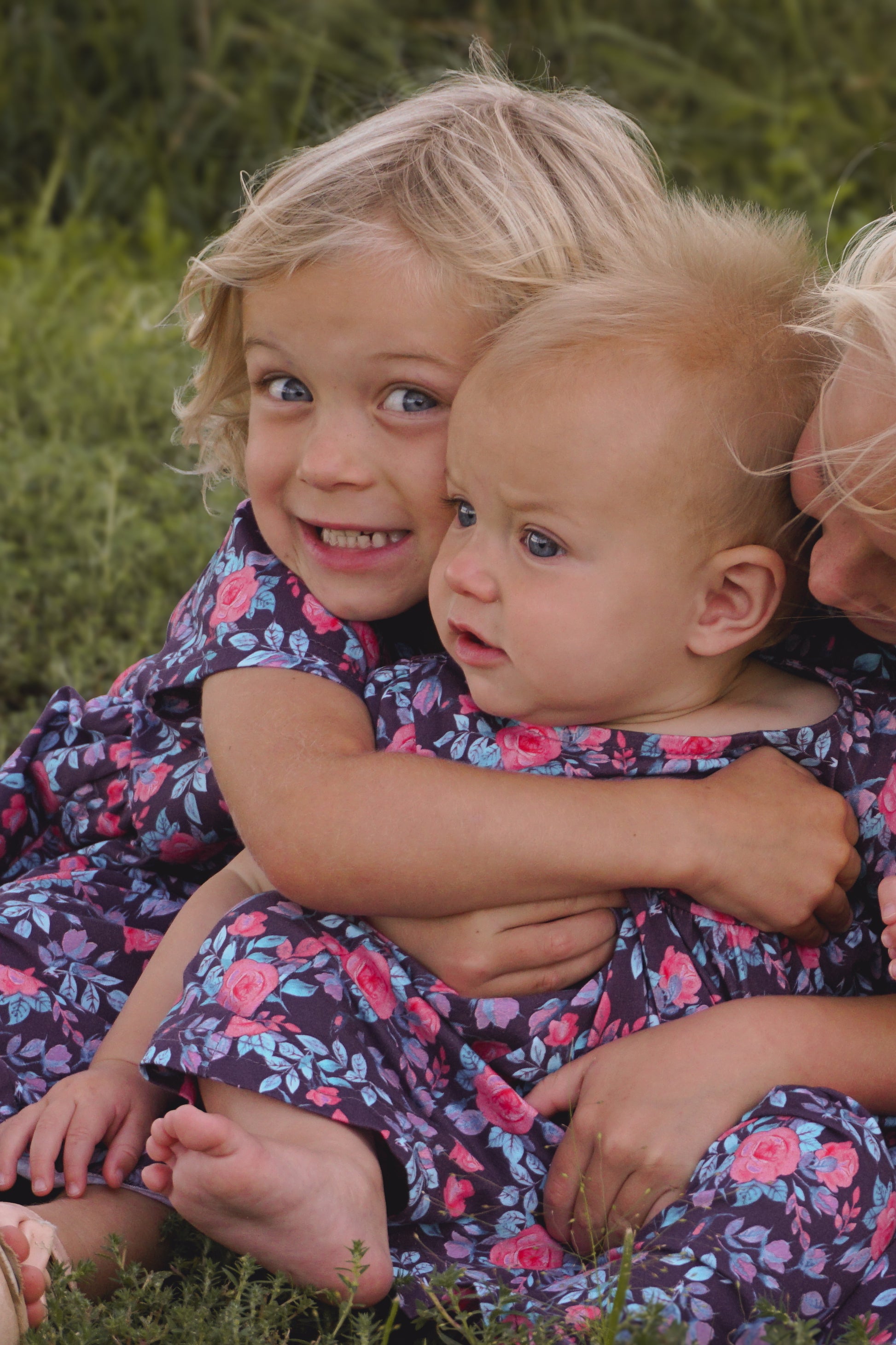 Three girls in matching floral dresses on grass