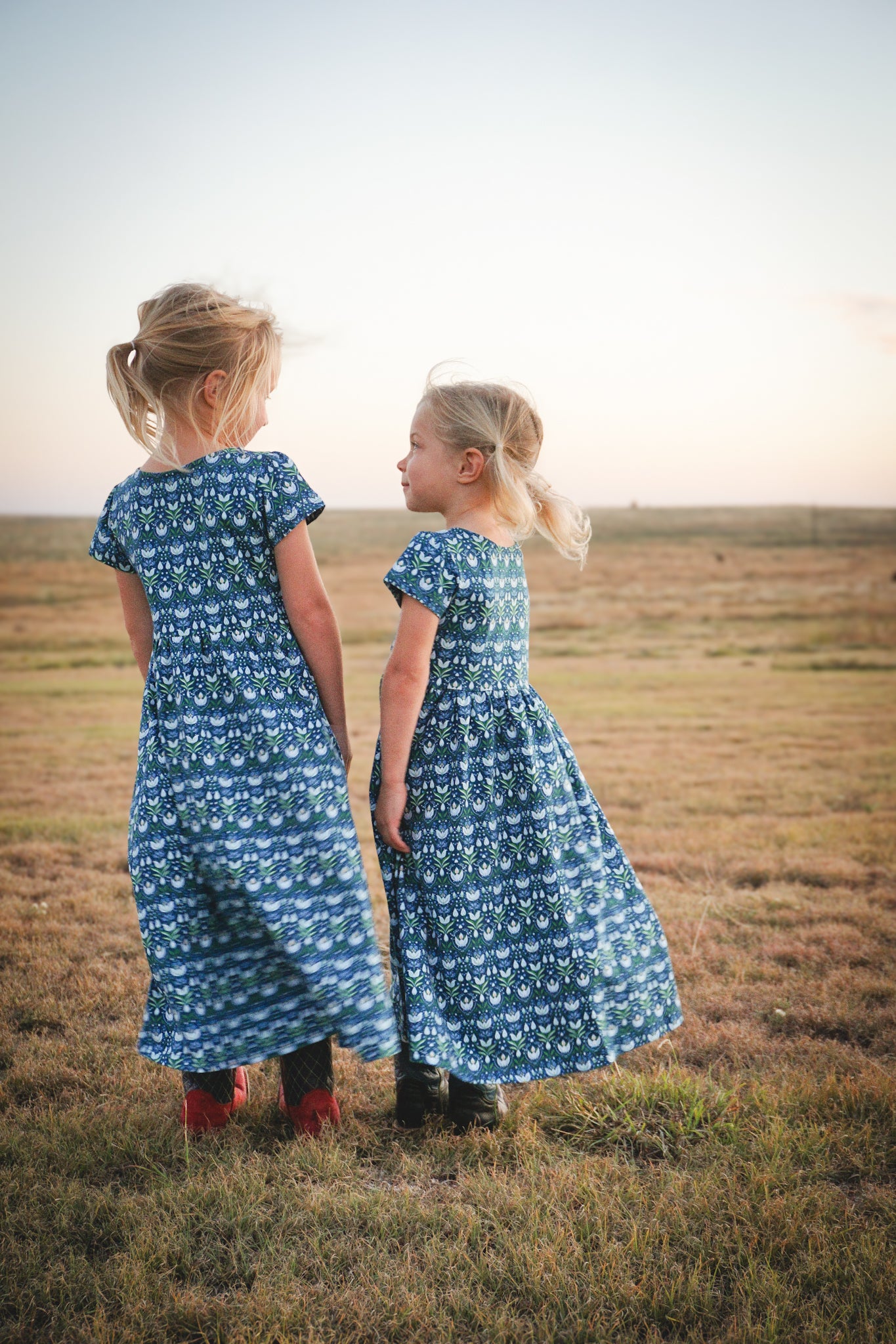 Two girls in modest nursing floral dresses in field