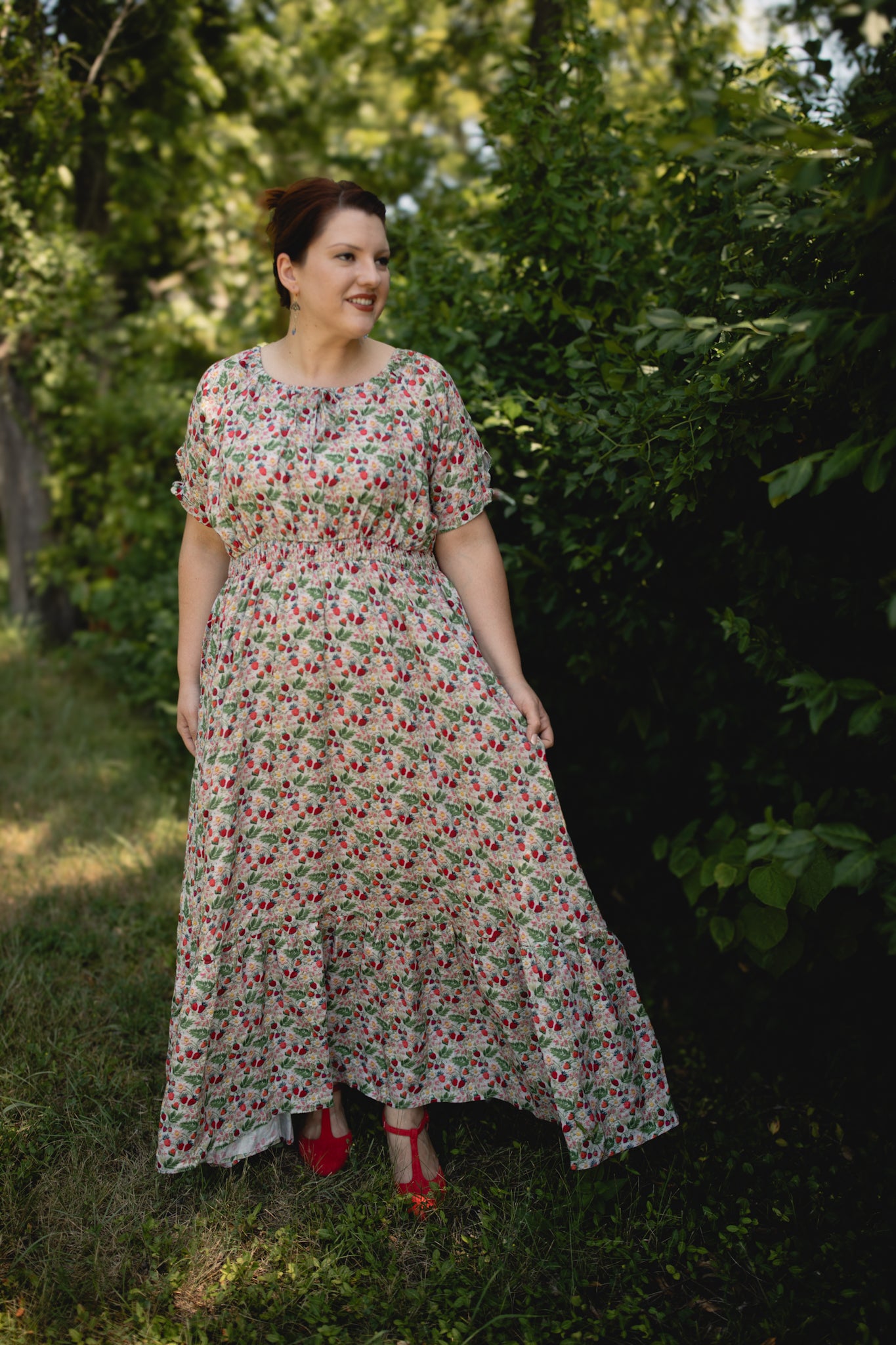 Woman in a floral modest nursing dress standing outdoors among trees
