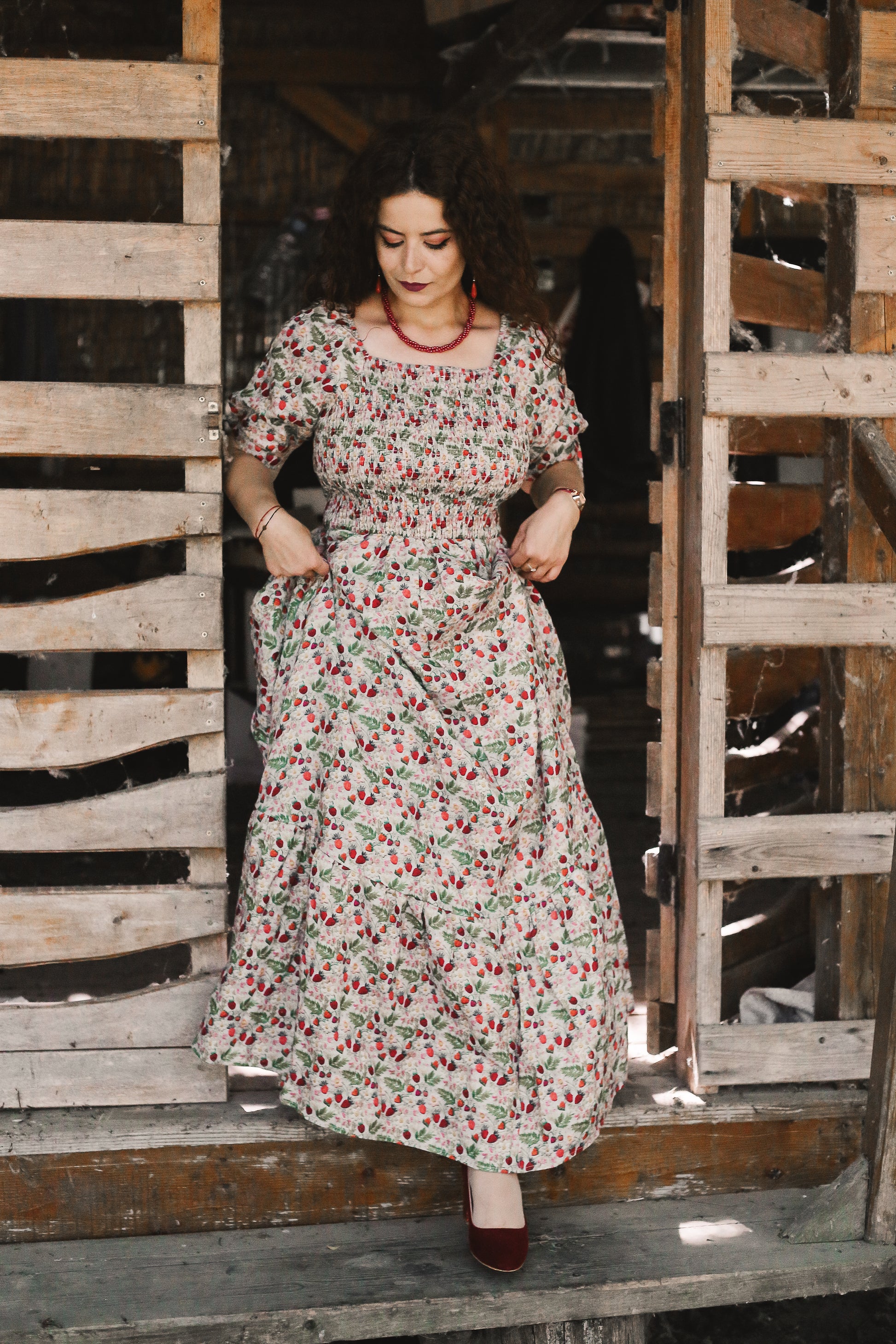 Woman in a floral modest nursing dress standing in front of wooden pallets