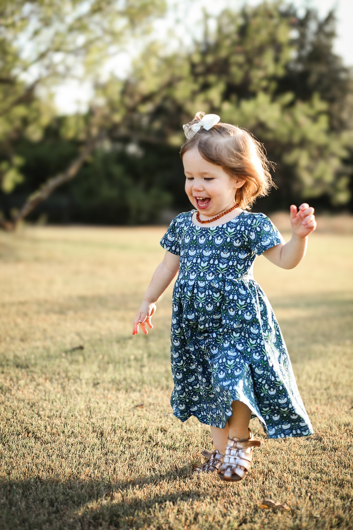 Child running in blue floral dress outdoors