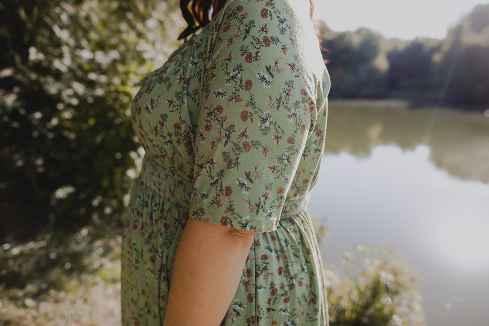 Woman in modest nursing floral dress by lake