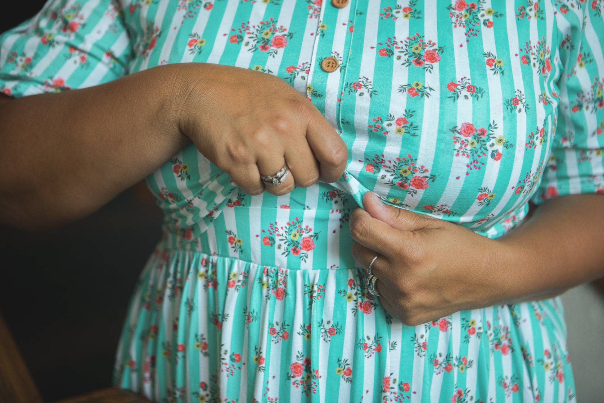 Person wearing a green and white striped modest nursing dress with floral patterns.